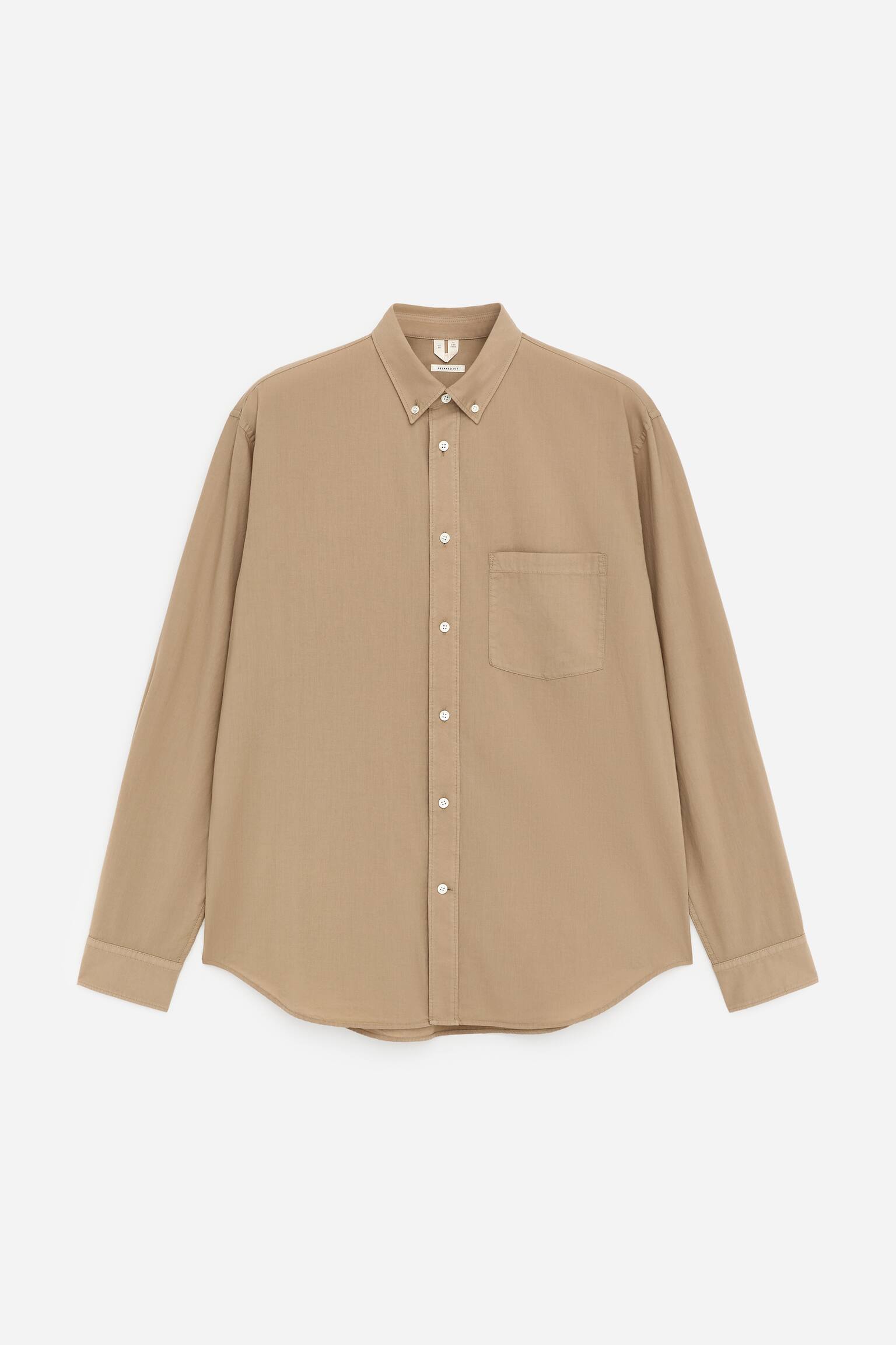 Una camicia color camoscio con bottoni è presentata dalla PARTE ANTERIORE, caratterizzata da un colletto con bottoni, un'abbottonatura completa con bottoni bianchi e una tasca applicata singola sul petto sinistro. Le maniche lunghe si estendono fino a polsini con bottoni, e un orlo curvo completa il design della camicia.