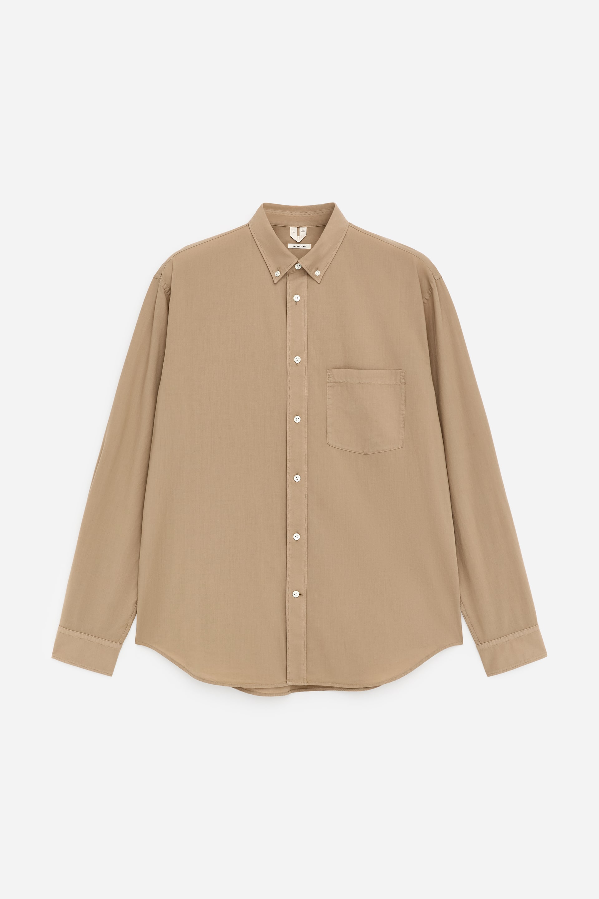 Visa större bild: En beige knappskjorta visas framifrån, med en knappkrage, en hel knappslå med vita knappar och en enda bröstficka på vänster sida. Långa ärmar sträcker sig till knäppta manschetter och en rundad fåll fullbordar skjortans design.