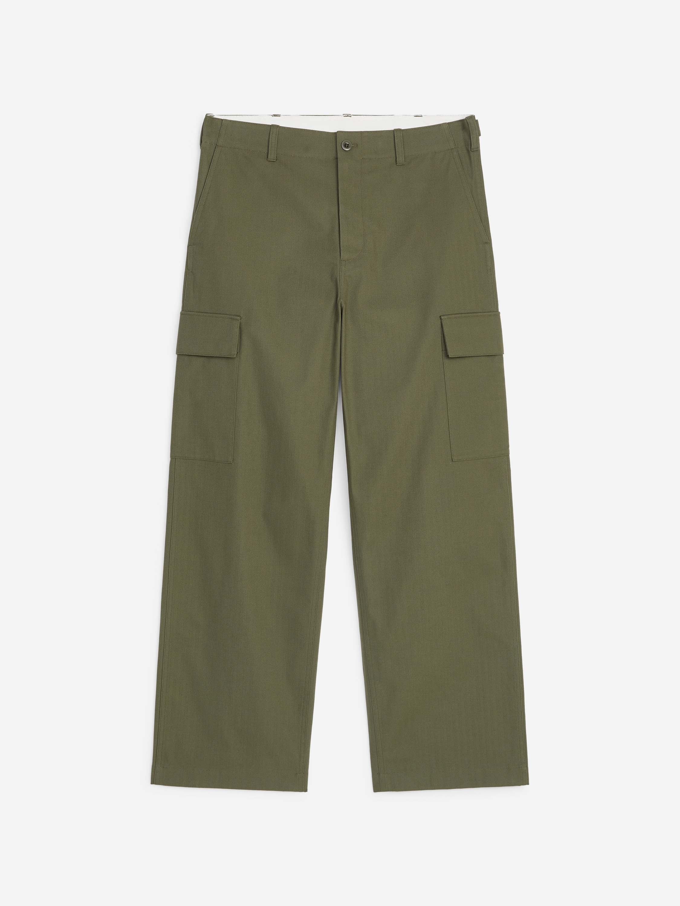 Une veste légère taupe, dotée d'une fermeture éclair complète à l'avant, d'un col pointu et de deux poches à rabat horizontales, est portée ouverte sur un t-shirt à col rond blanc. Un pantalon cargo vert olive à jambes larges, avec des poches cargo latérales et maintenu par une ceinture en cuir tressé marron foncé, complète l'ensemble avec des mocassins en cuir noir, tous orientés vers l'avant.