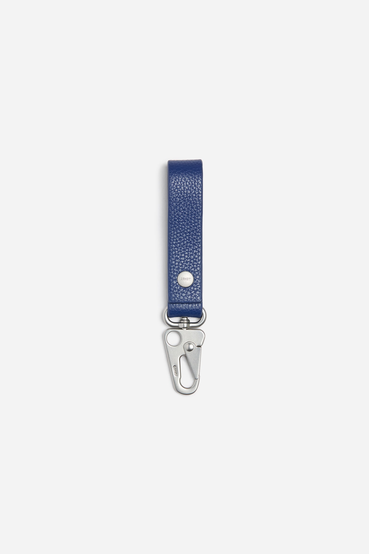 Un porte-clÃ©s en cuir texturÃ© bleu est prÃ©sentÃ© de face, avec une laniÃ¨re en boucle fixÃ©e par un bouton-pression en mÃ©tal argentÃ©. La laniÃ¨re se termine par un crochet Ã  pression en mÃ©tal argentÃ© en bas.