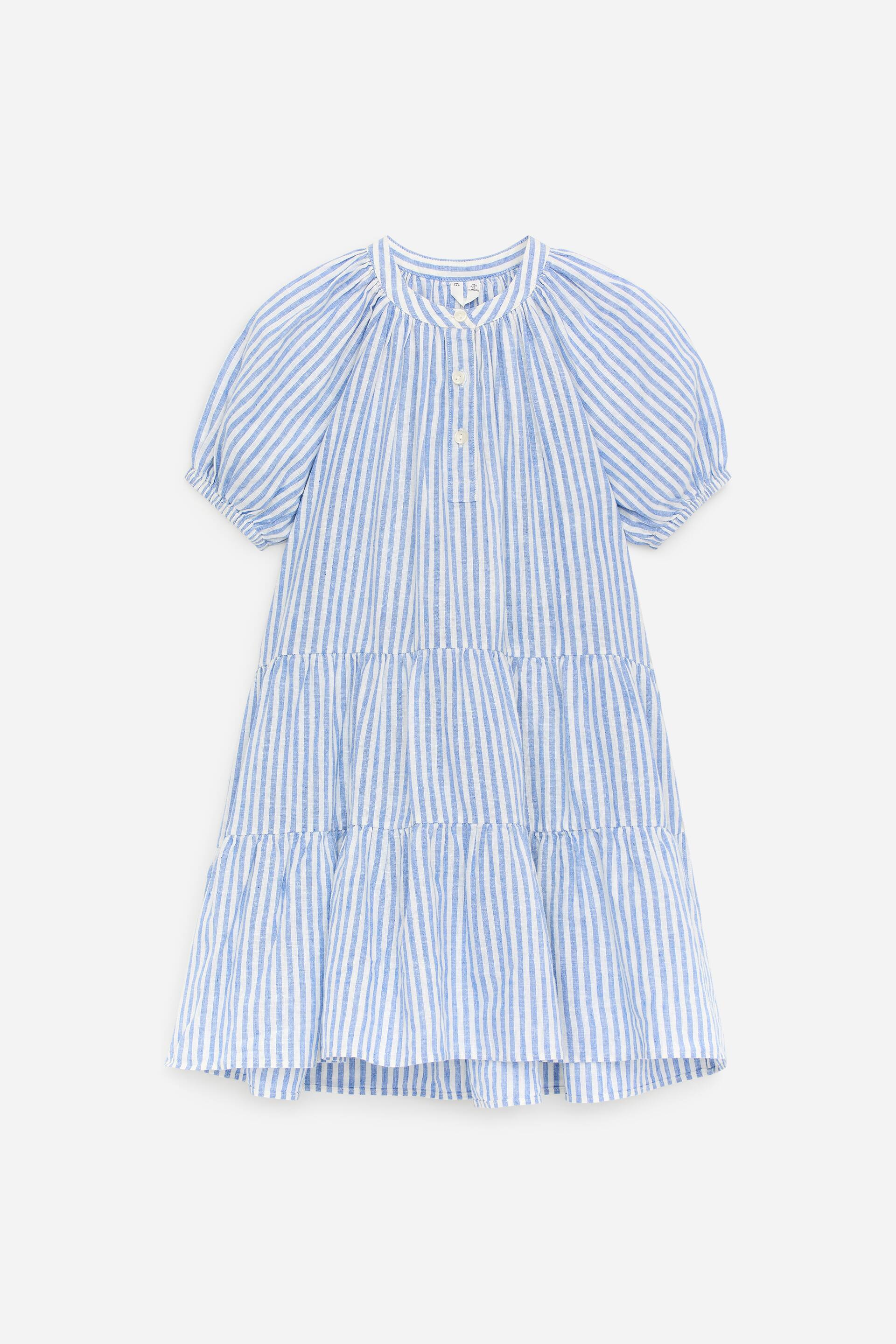 View larger image: A blue and white striped dress featuring a band collar and a partial button placket with three white buttons, designed with short puffed sleeves and a tiered skirt consisting of two gathered panels.