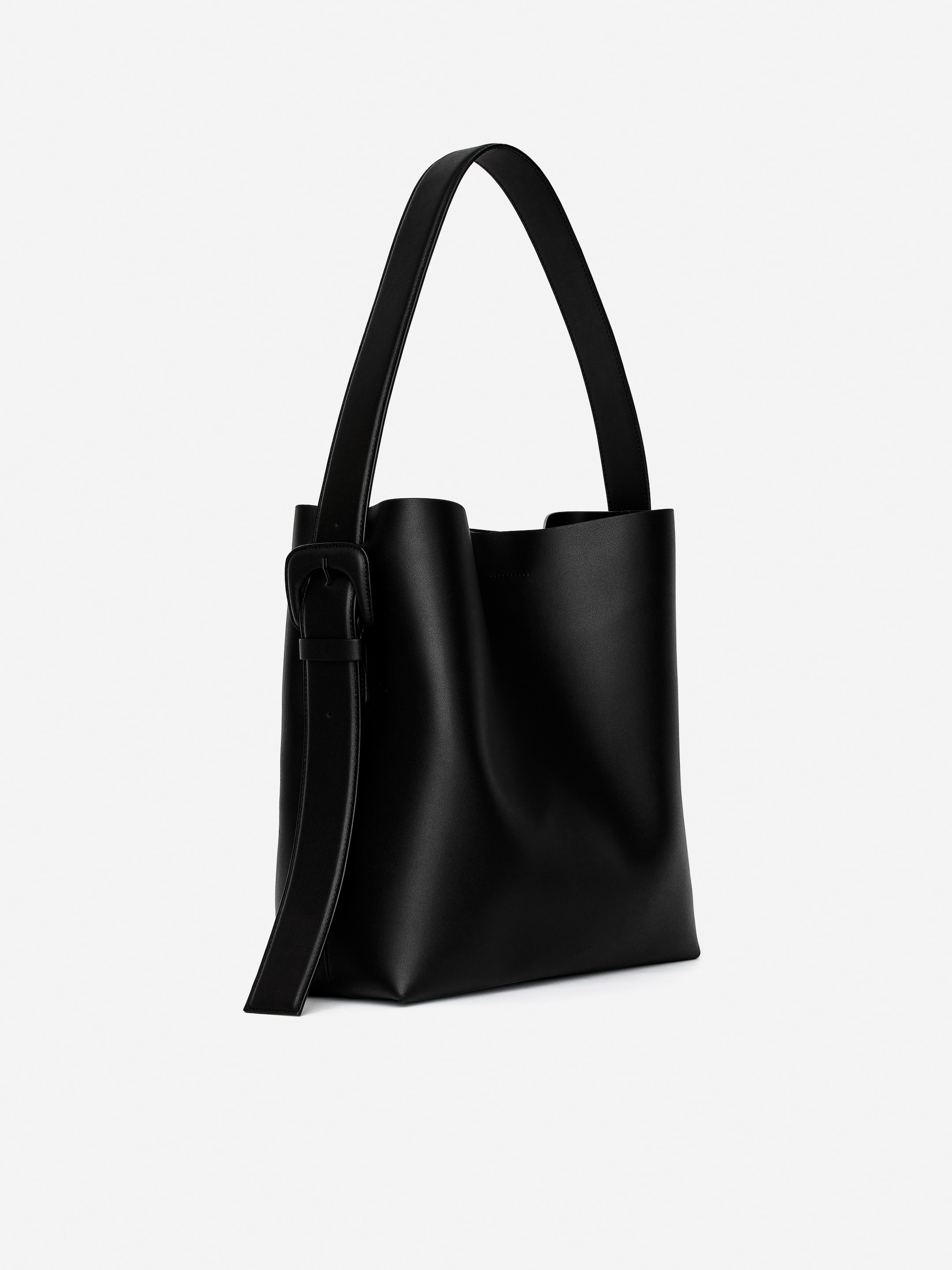 Vis større bilde: En svart totebag presenteres med en semi-rigid struktur, vinklet mot venstre, og har en enkelt skulderstropp med en spenne-detalj.