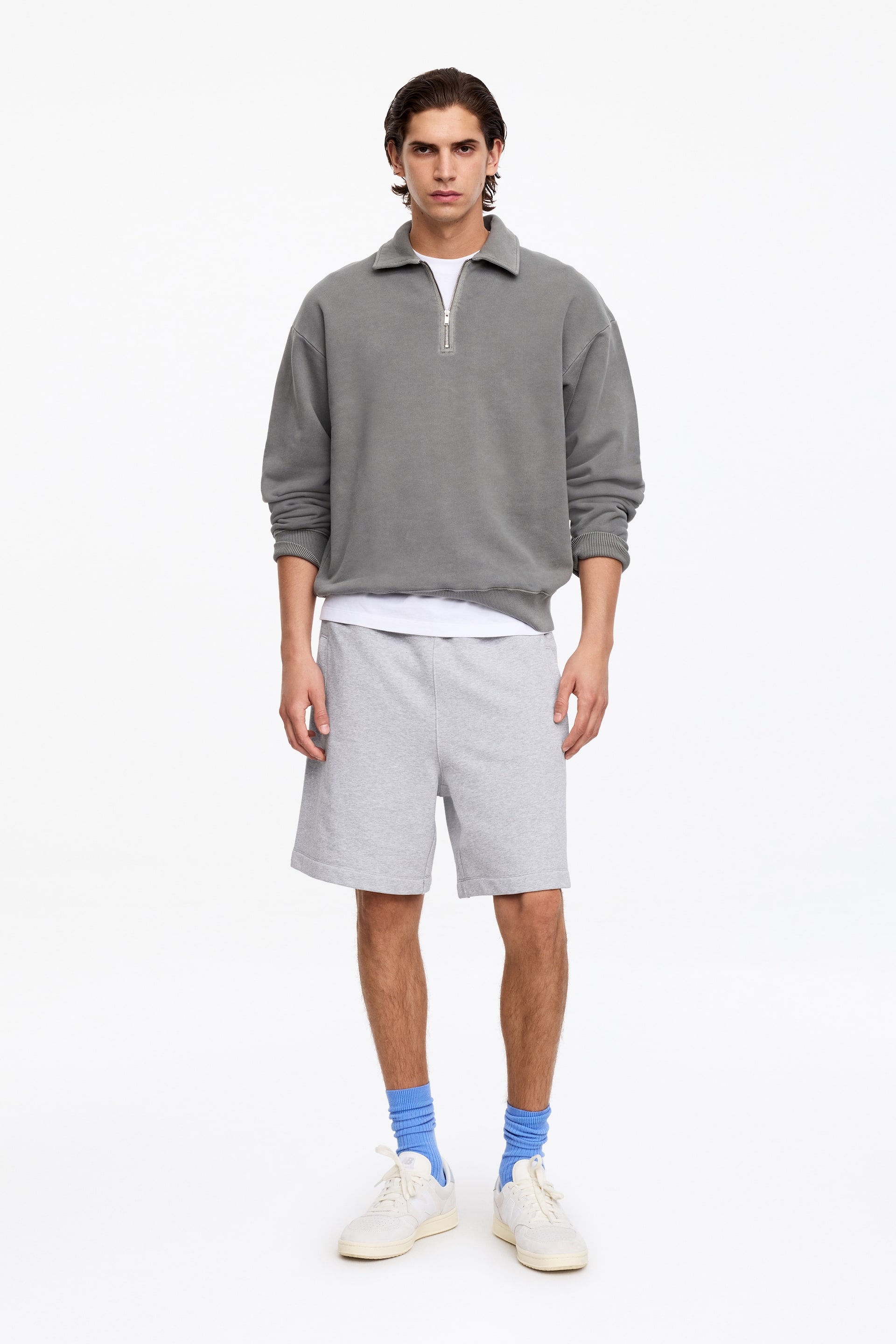 Agrandir l'image: Un sweat-shirt gris à fermeture éclair quart est présenté de face, avec un col évasé et une fermeture éclair argentée. Il affiche une coupe décontractée avec des épaules tombantes, des poignets côtelés et un ourlet côtelé, superposé sur un t-shirt blanc.