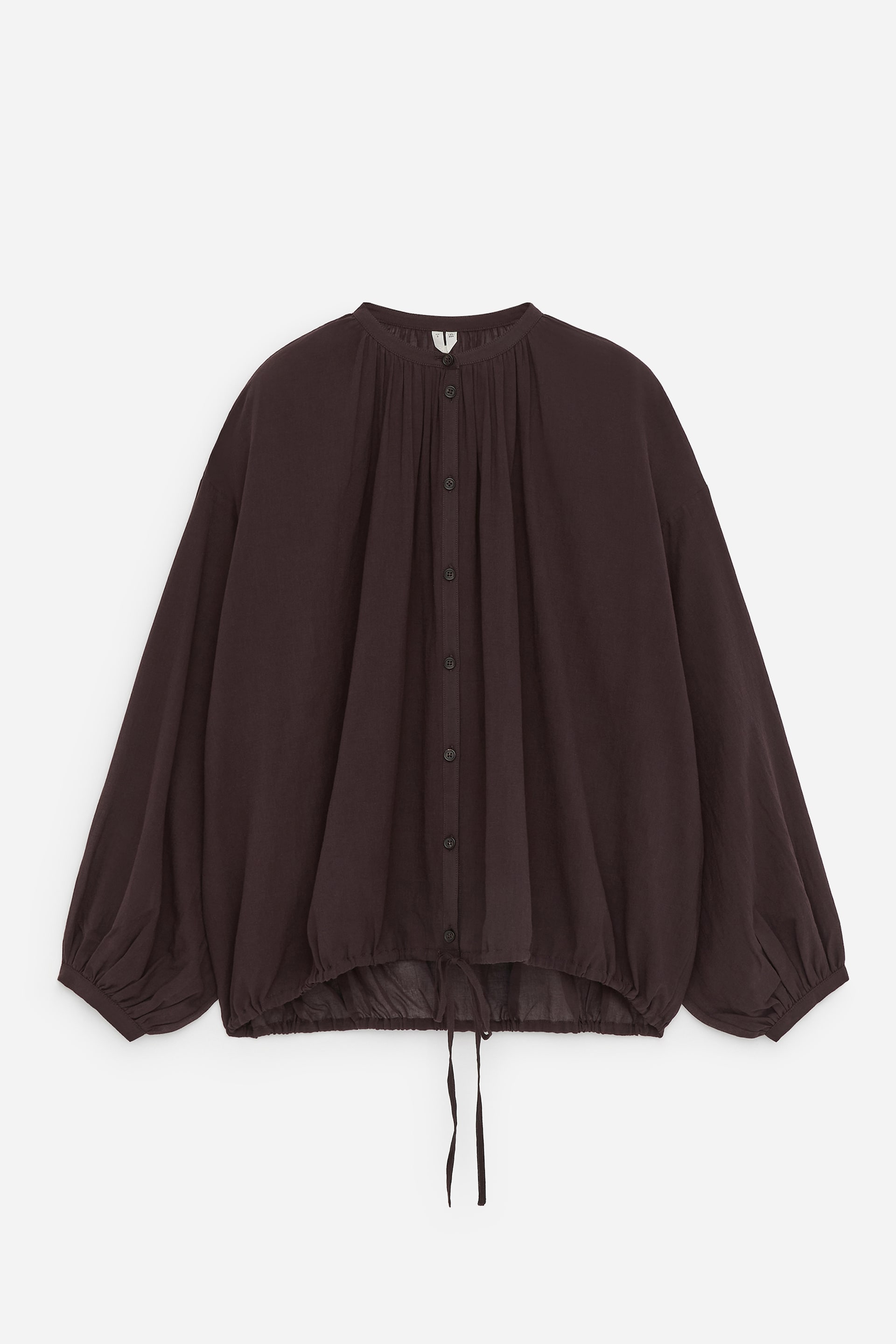 Visualizza immagine più grande: Una blusa marrone scuro è presentata frontalmente, caratterizzata da un colletto a fascia e un'abbottonatura completa. Presenta arricciature intorno allo scollo, maniche lunghe voluminose con polsini arricciati e un orlo con coulisse con lacci visibili che stringono il fondo.