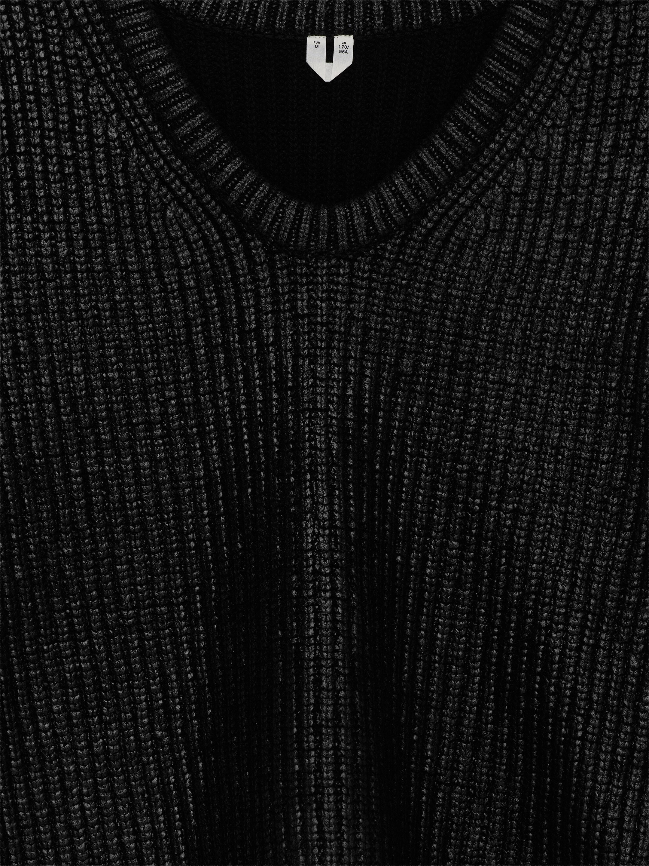 Visualizza immagine più grande: Un maglione nero con scollo a V presenta una distintiva trama a coste sul davanti, con un'etichetta bianca della taglia appena sotto la scollatura.