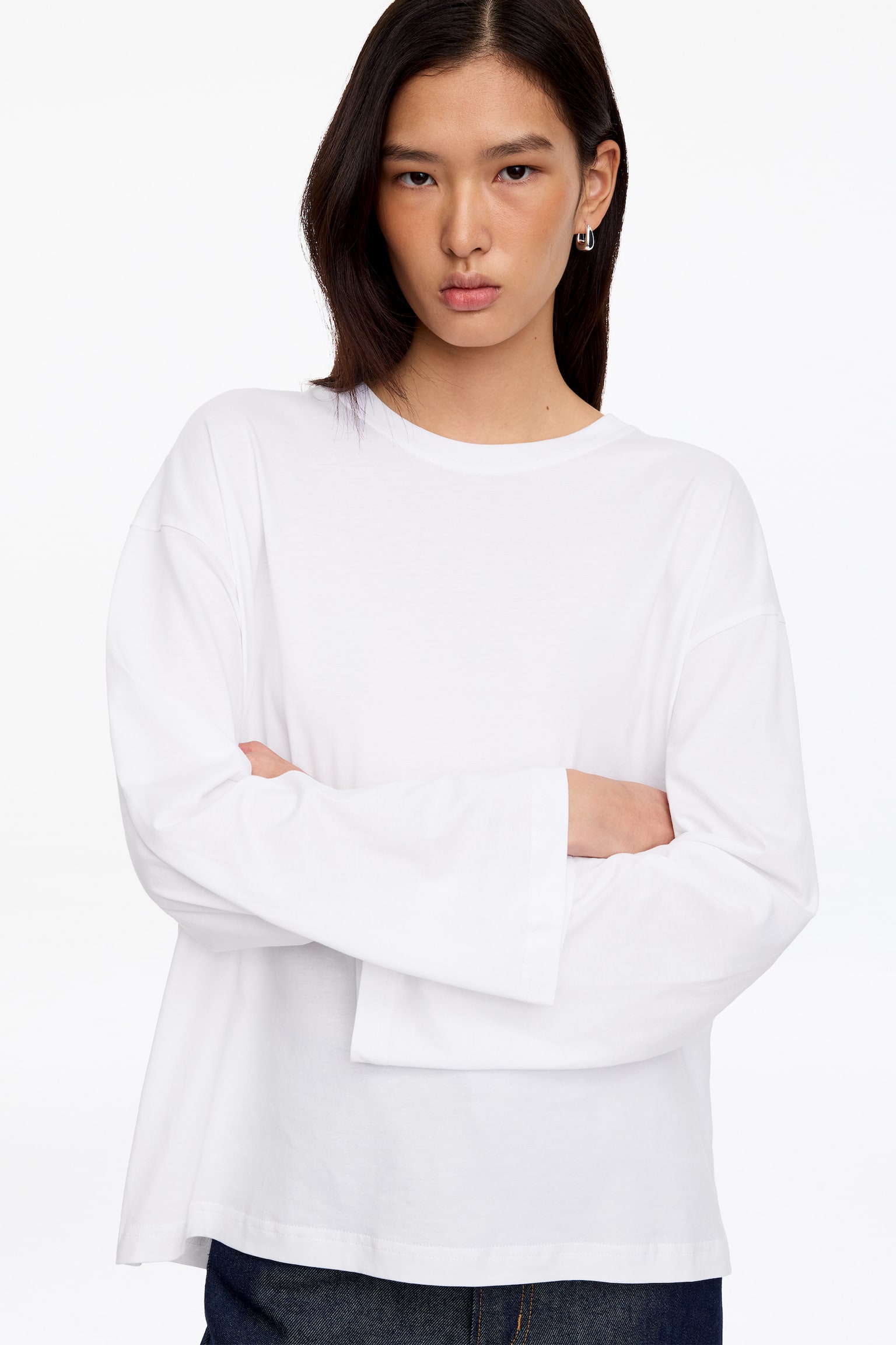 Un tricou alb oversized cu mâneci lungi este prezentat din față, având guler rotund, mâneci largi cu manșete drepte și o siluetă lejeră. - 1