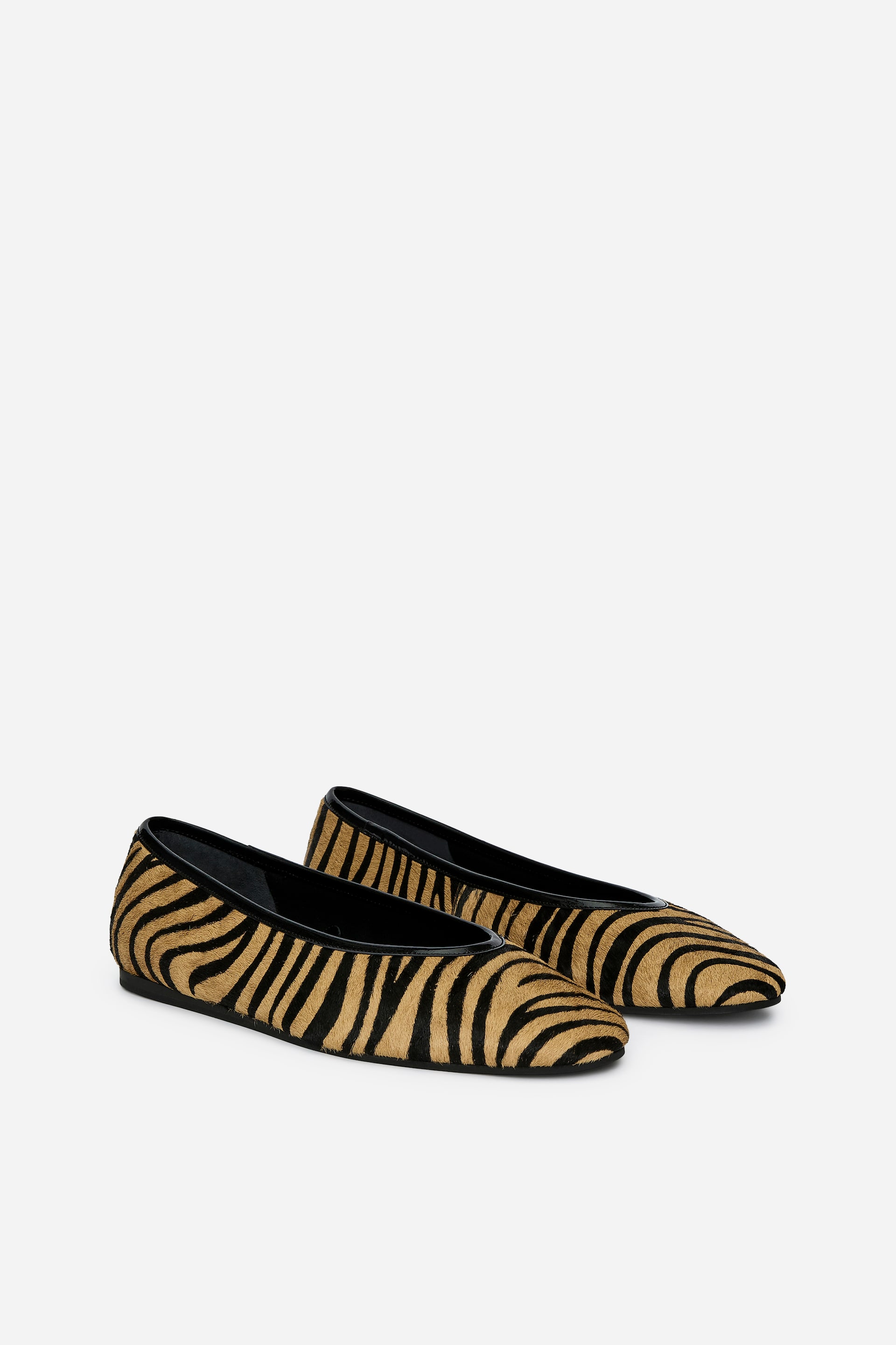 Visualizza immagine più grande: Un paio di ballerine a punta presenta un motivo a strisce di zebra tan e nero. Ogni ballerina sfoggia un bordo nero intorno all'apertura, e la ballerina in primo piano è inclinata verso SINISTRA, mostrando il lato e la parte anteriore.