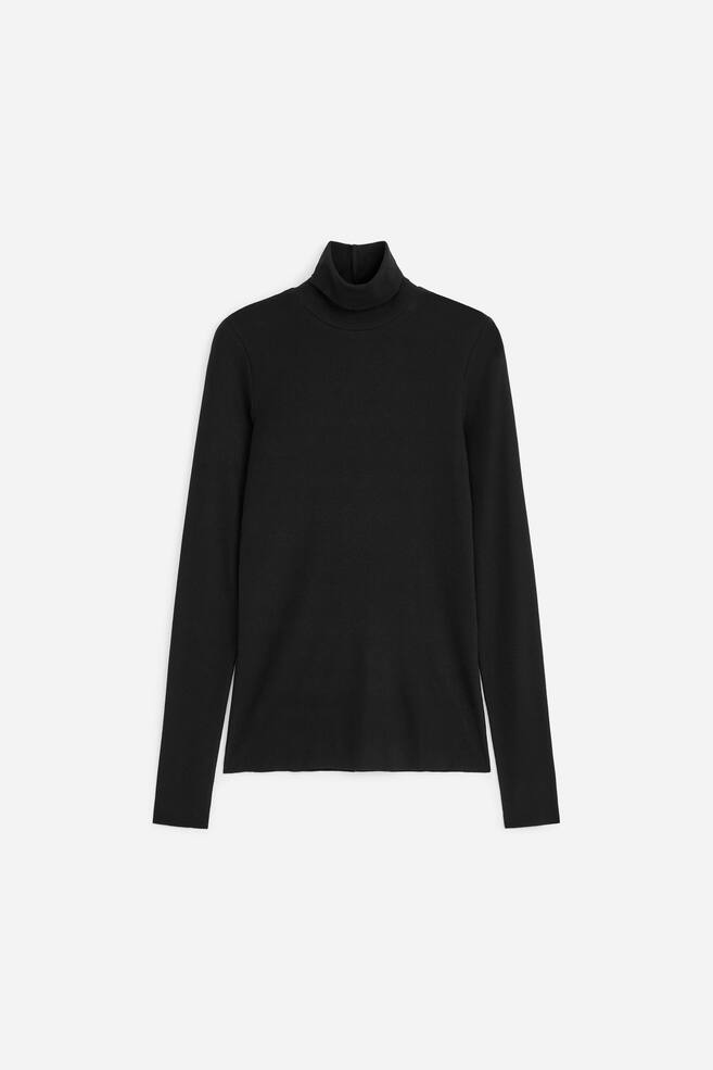 A black roll-neck jersey top is shown front-facing, featuring a folded polo-neck collar, long sleeves, and a straight hem. - 1