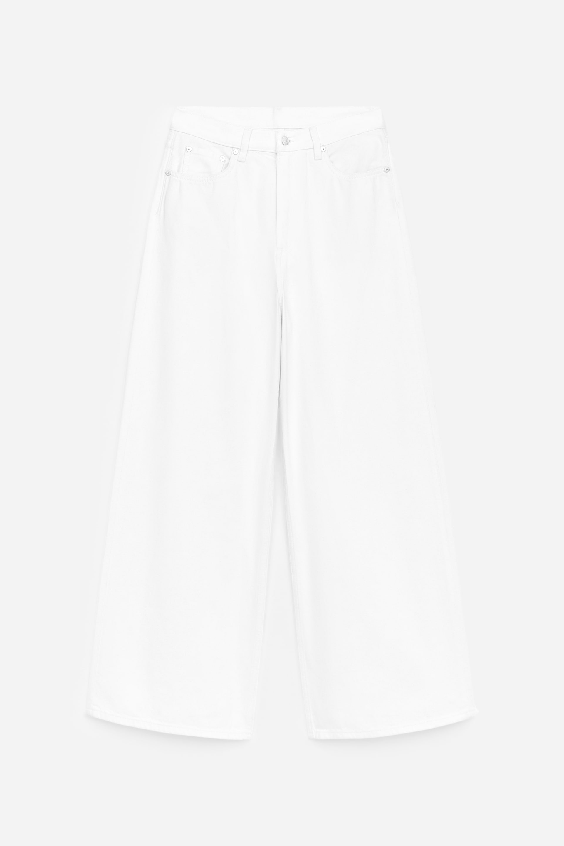 Visa större bild: Vita, vida byxor visas framifrån, med knapp- och dragkedjeförslutning, två framfickor, en liten myntficka och en hög midja.