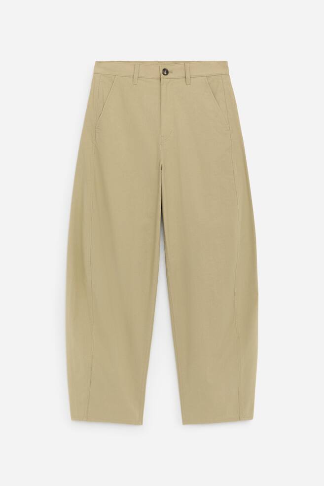 The light tan cotton trousers are showcased from the FRONT, featuring barrel-shaped legs and a mid-rise waist. They are designed with slanted side pockets and a zip and button fastening. - 1