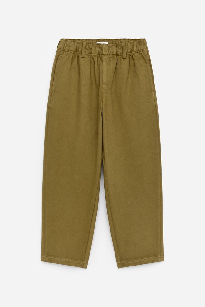 Die VORDERSEITE der entspannten Chino-Hose präsentiert einen elastischen Bund mit sichtbaren Gürtelschlaufen, seitlichen Eingrifftaschen und einem gesteppten Fake-Reißverschluss. - 1
