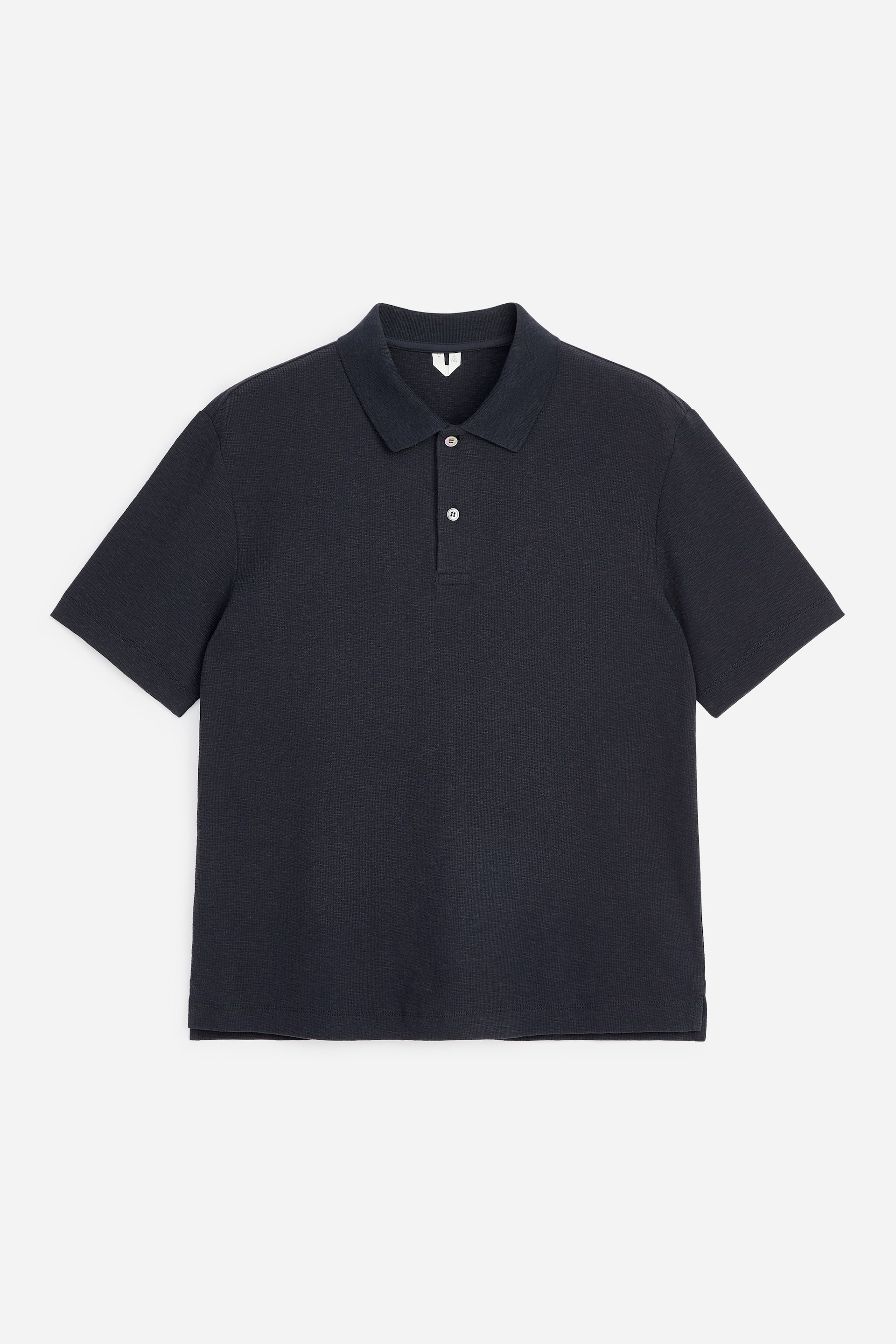 Ver imagen más grande: Una camiseta polo gris oscuro está de frente, mostrando un cuello clásico y una tapeta de dos botones con botones de color claro. Presenta mangas cortas y un tejido de punto texturizado.