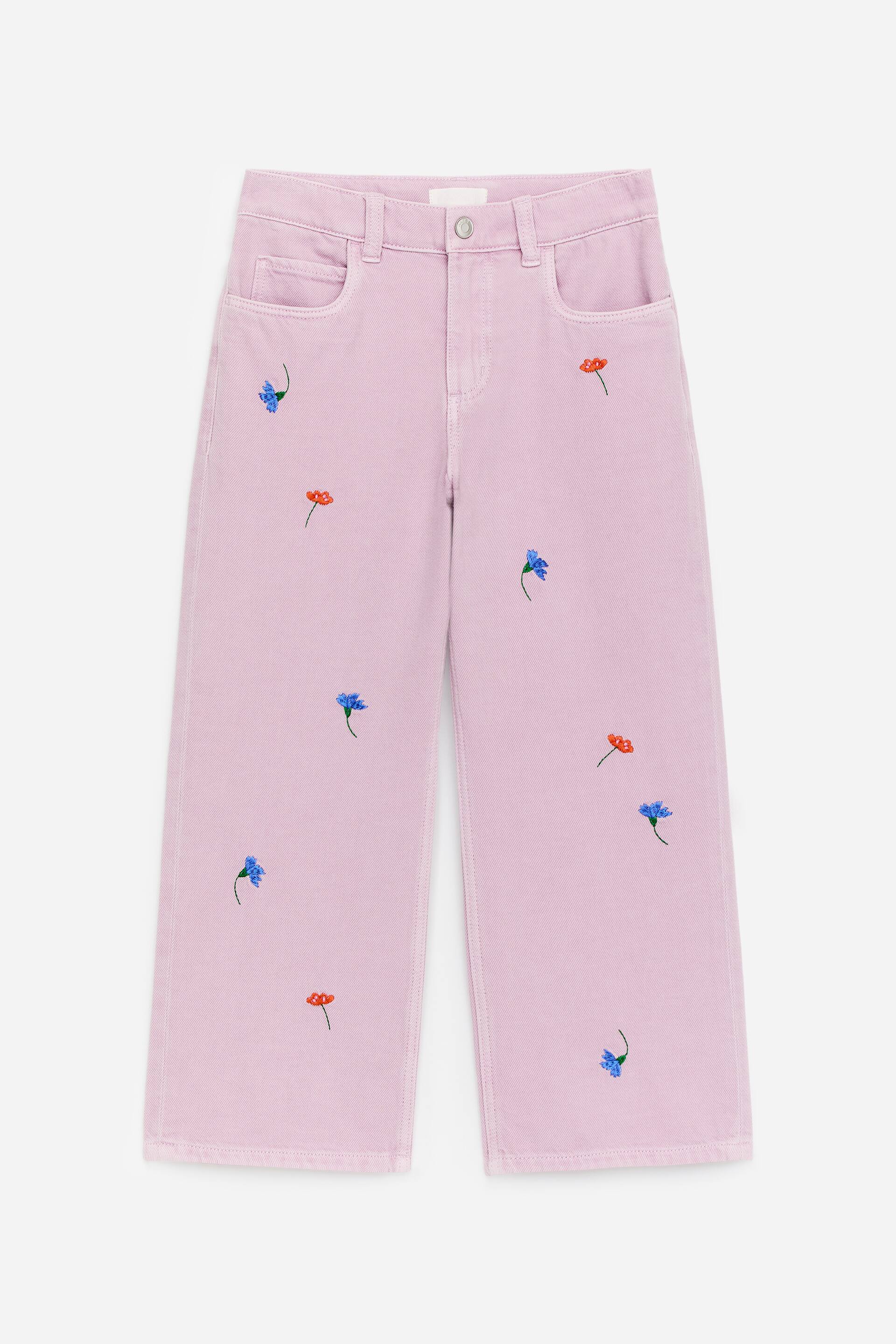 Zobraziť väčší obrázok: Ružové denimové nohavice sú prezentované spredu, obsahujú klasický 5-vreckový štýl, voľný strih a roztrúsené vyšívané kvety v modrej a červenej farbe.