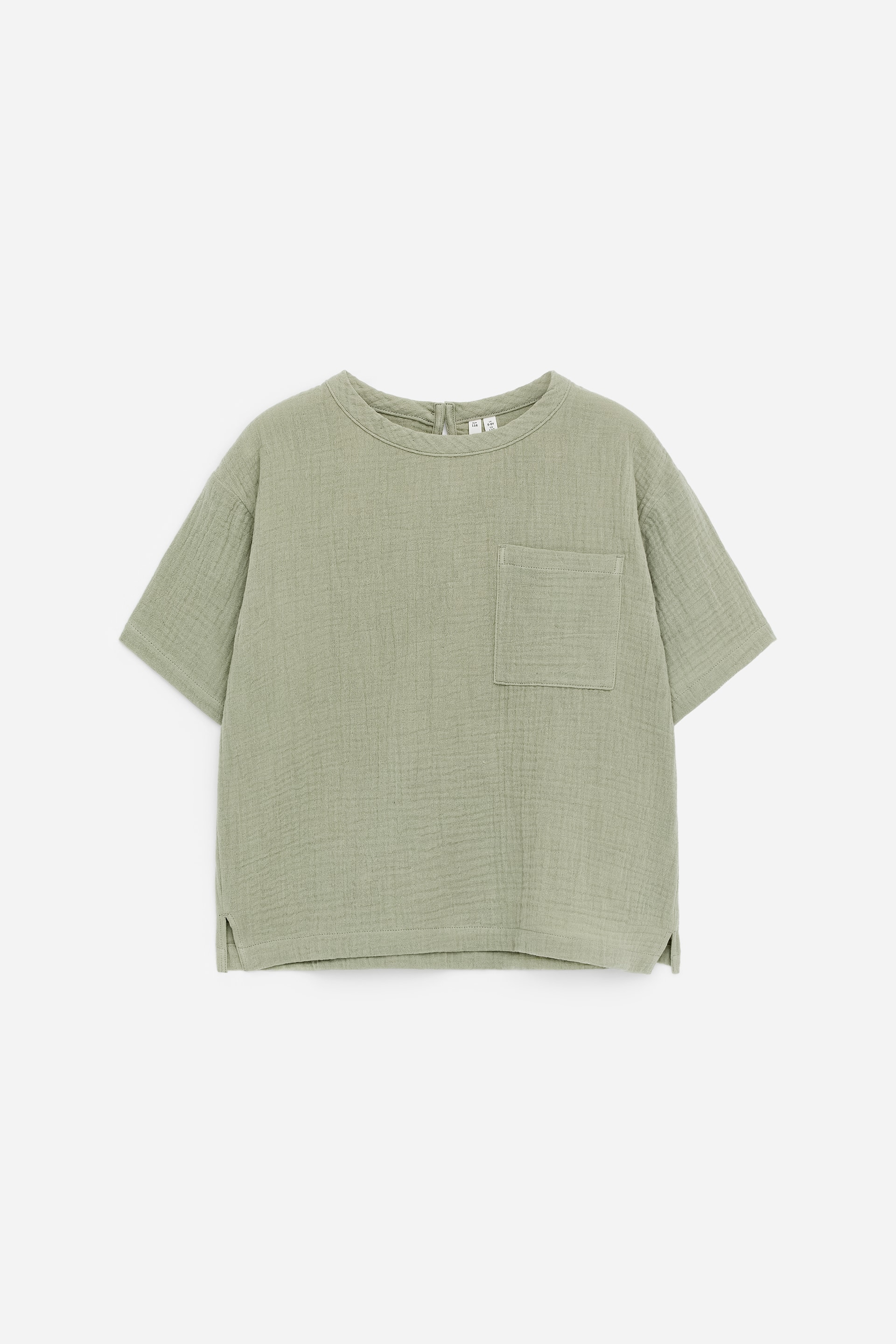 Nagyobb kép megtekintése: Világoszöld, rövid ujjú felső, amely az elejét mutatja be, ráncos textúrával, kerek nyakkal, hátul kis cipzáras záródással, bal mellkason egy foltzsebbel, és az alján kis oldalsó hasítékokkal.