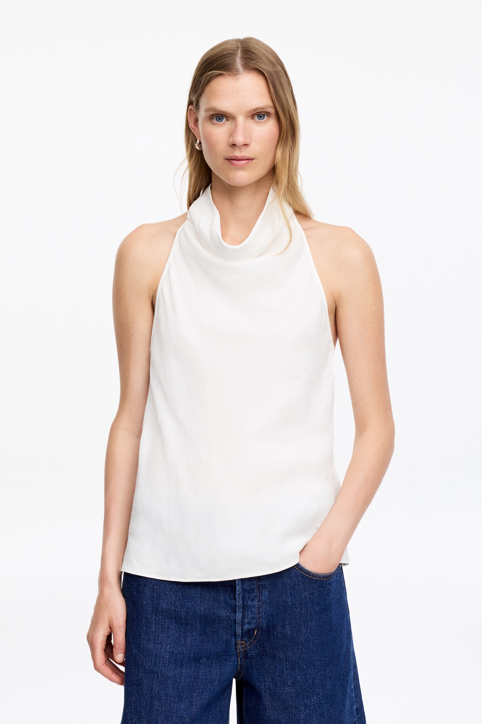 Visa större bild: Ett vitt halterneck-linne med en draperad cowl-krage och en avslappnad, ärmlös design. Det visas framifrån.