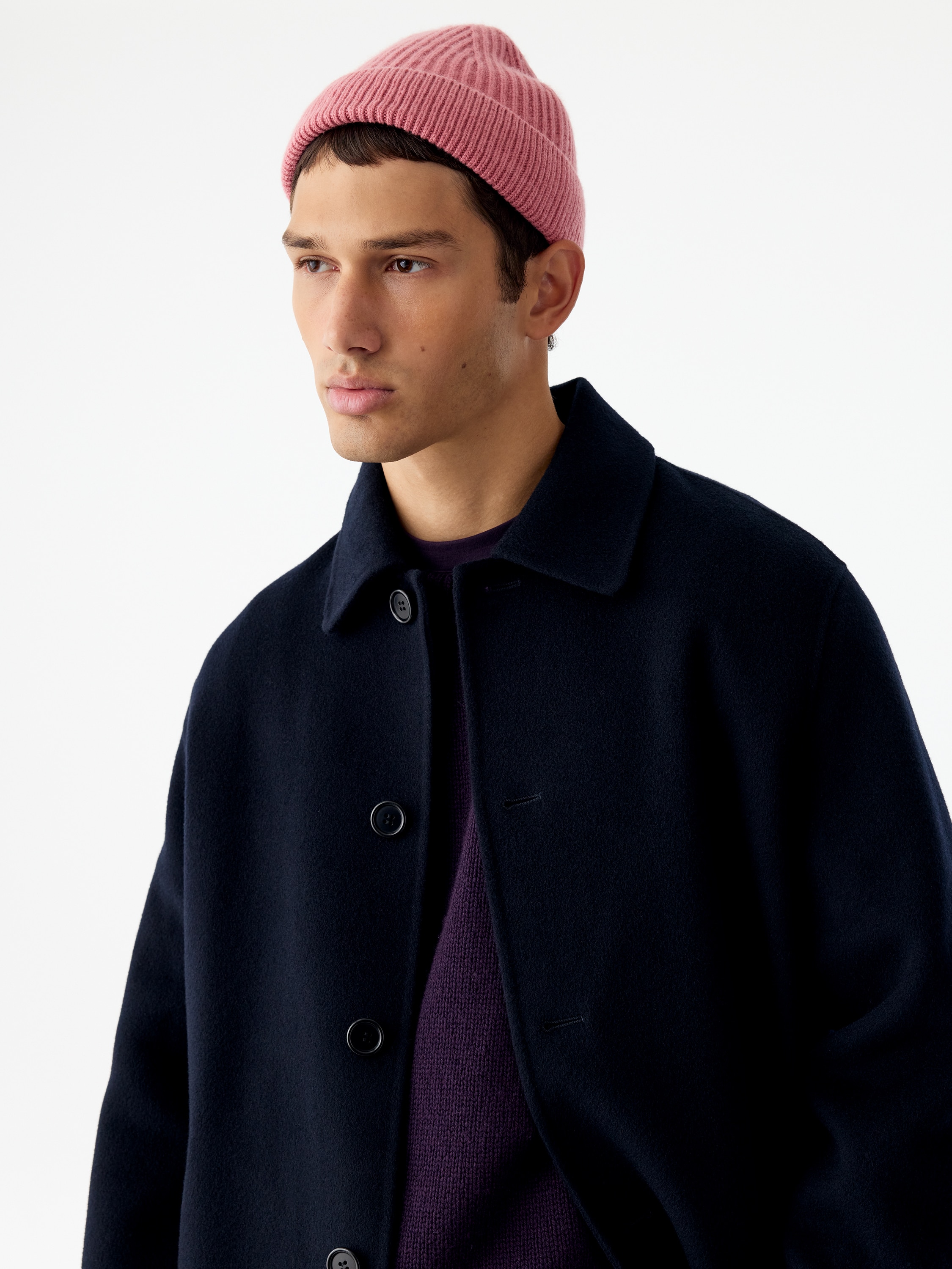A pink ribbed knit beanie is shown from the front, featuring a wide folded cuff and a structured, domed crown with vertical ribbing converging at the top.