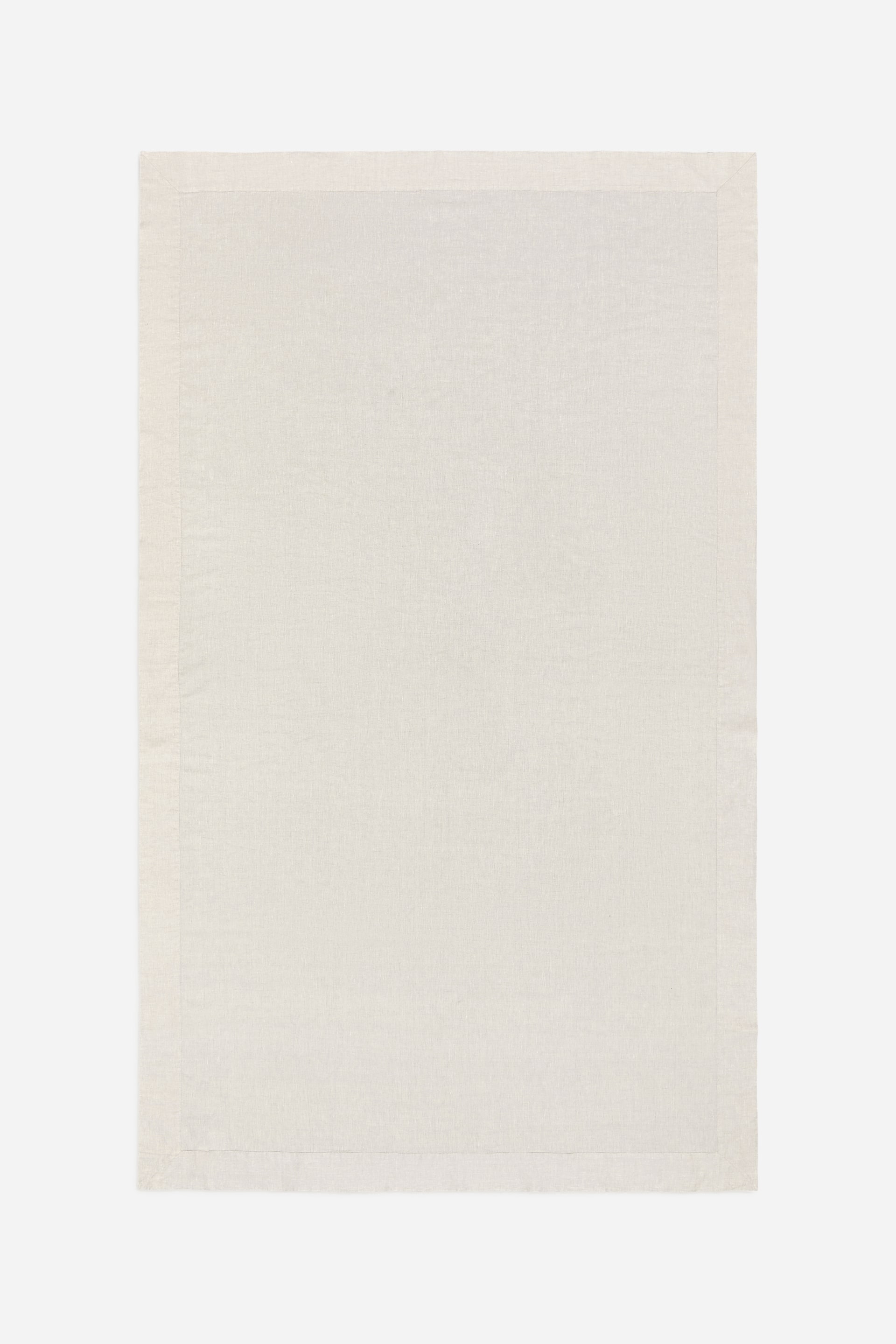 Ver imagen más grande: Una alfombra rectangular de tela color crema muestra una textura finamente tejida. Sus bordes están acabados con un dobladillo visible, creando un borde limpio.