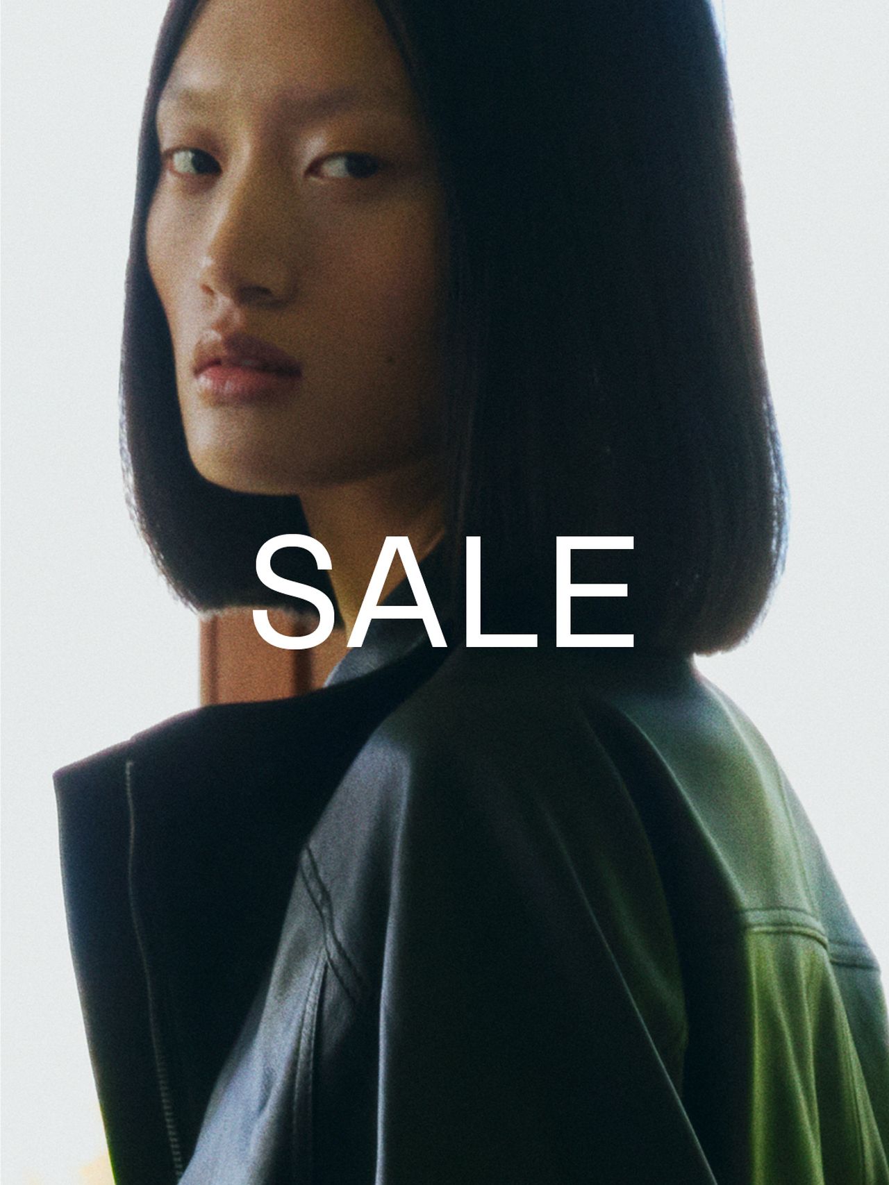 Person with straight black hair wearing a leather jacket, looking over their shoulder. The word "SALE" is prominently displayed on the image.