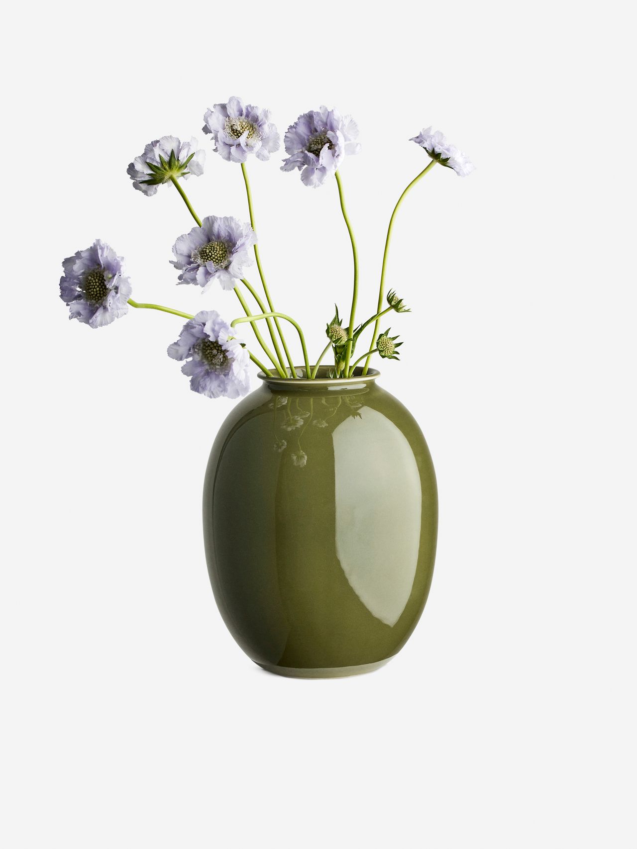 Arket green vase with delicate purple flowers on long stems against a plain white background.