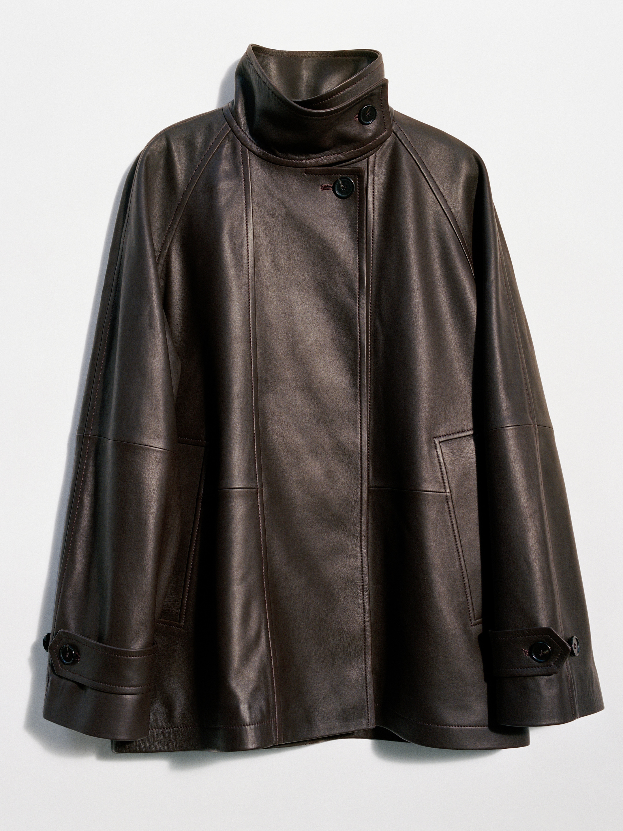 Dark brown leather jacket with a high collar and button details, hanging on a white background.