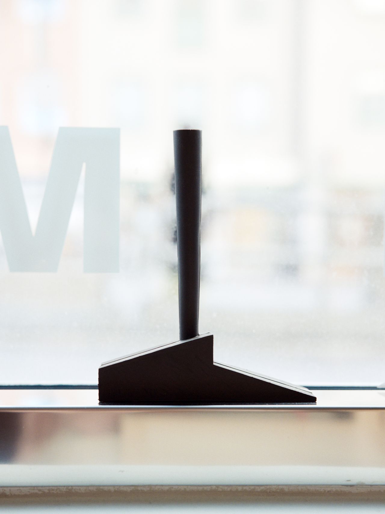 A modern, minimalist doorstop with a sleek, angular design placed on a windowsill.