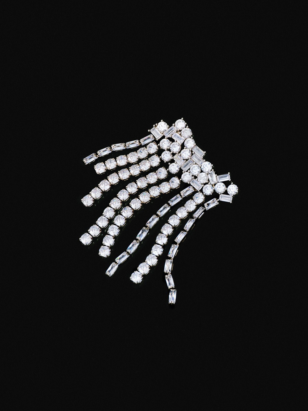A sparkling diamond brooch with cascading strands set against a black background.