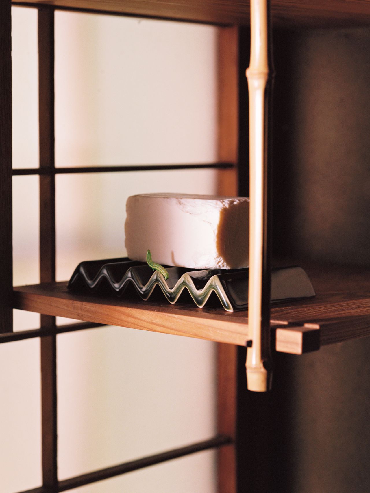 A block of tofu on a zigzag-patterned tray, placed on a wooden shelf with vertical wooden slats in the background.