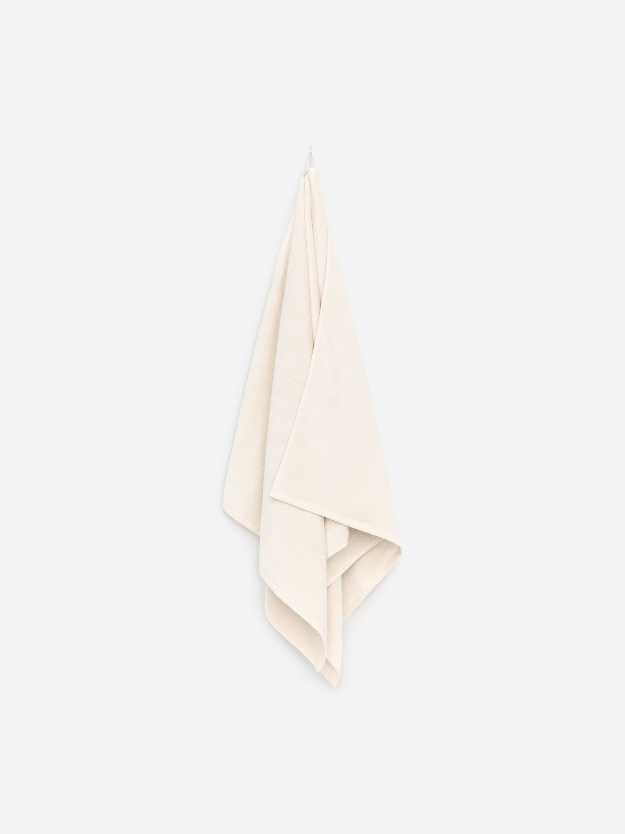 A soft, cream-colored towel hangs against a plain white background.