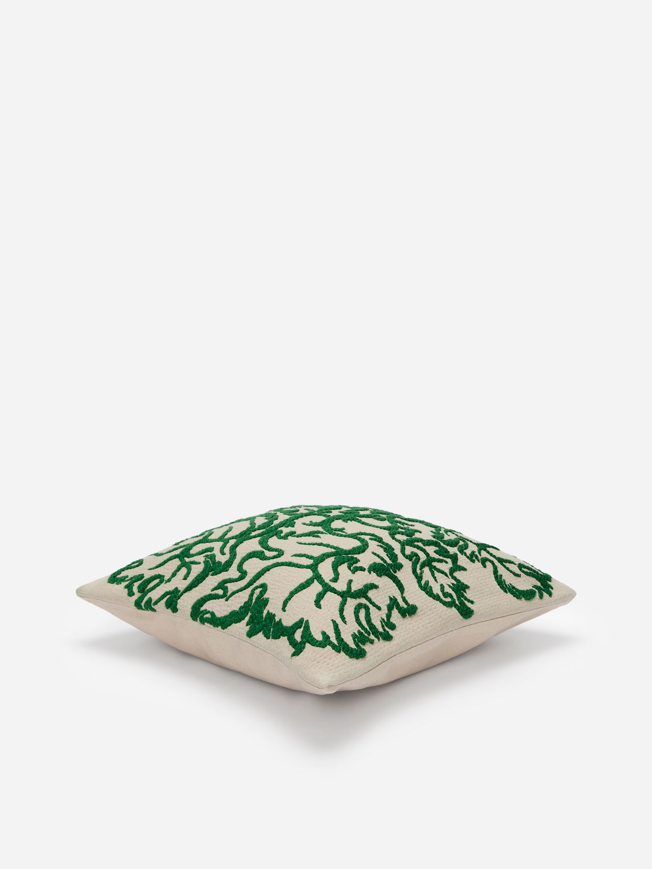 Square cushion with a beige background and green embroidered floral patterns, placed on a white surface.