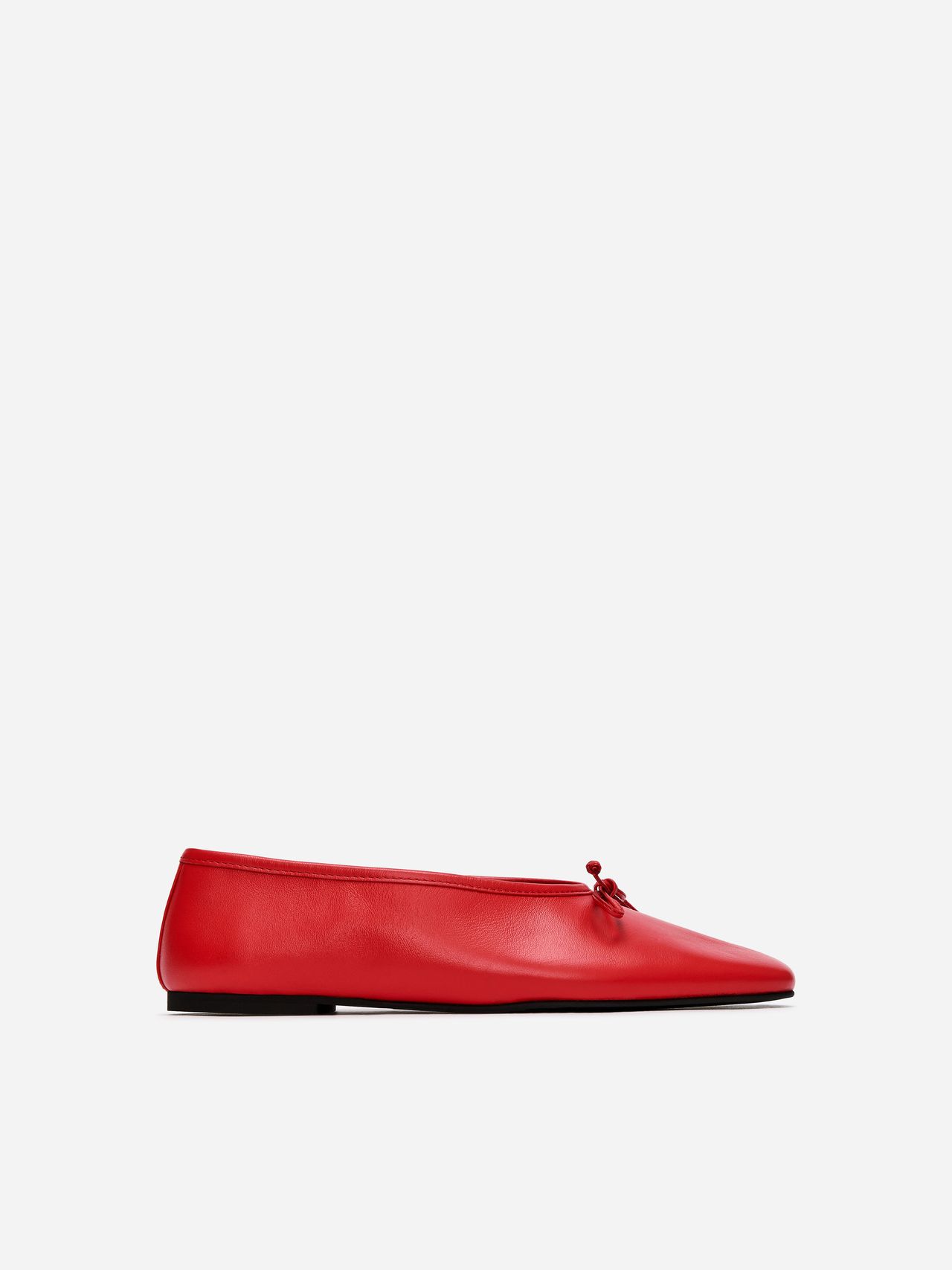 Red ballet flat with a small bow on top, side view, set against a plain white background.