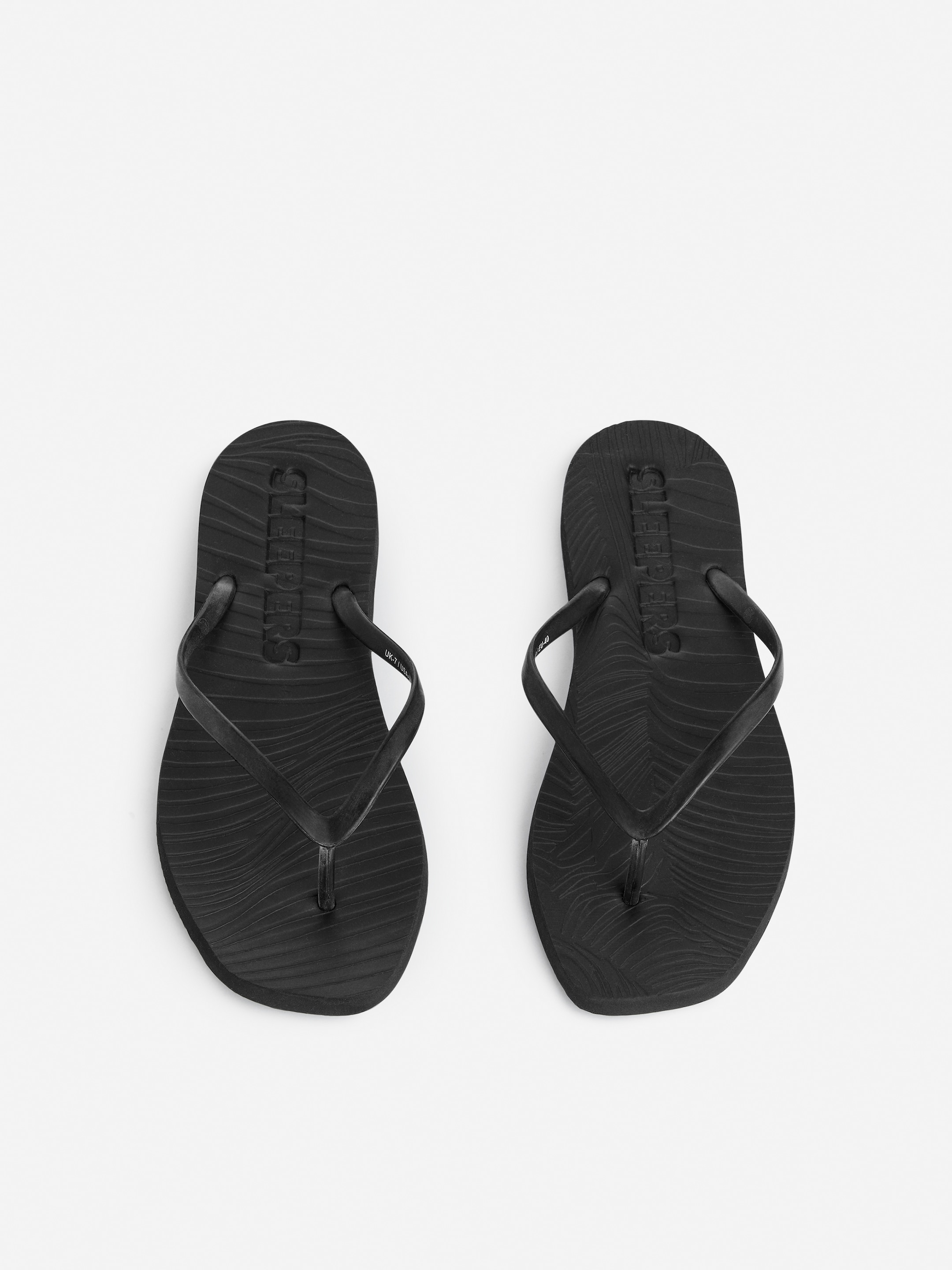 A pair of black flip-flops with textured soles, placed side by side on a light background.