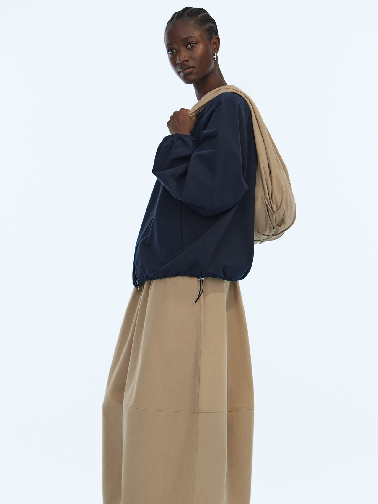 Woman in blue jacket and beige skirt holding a bag