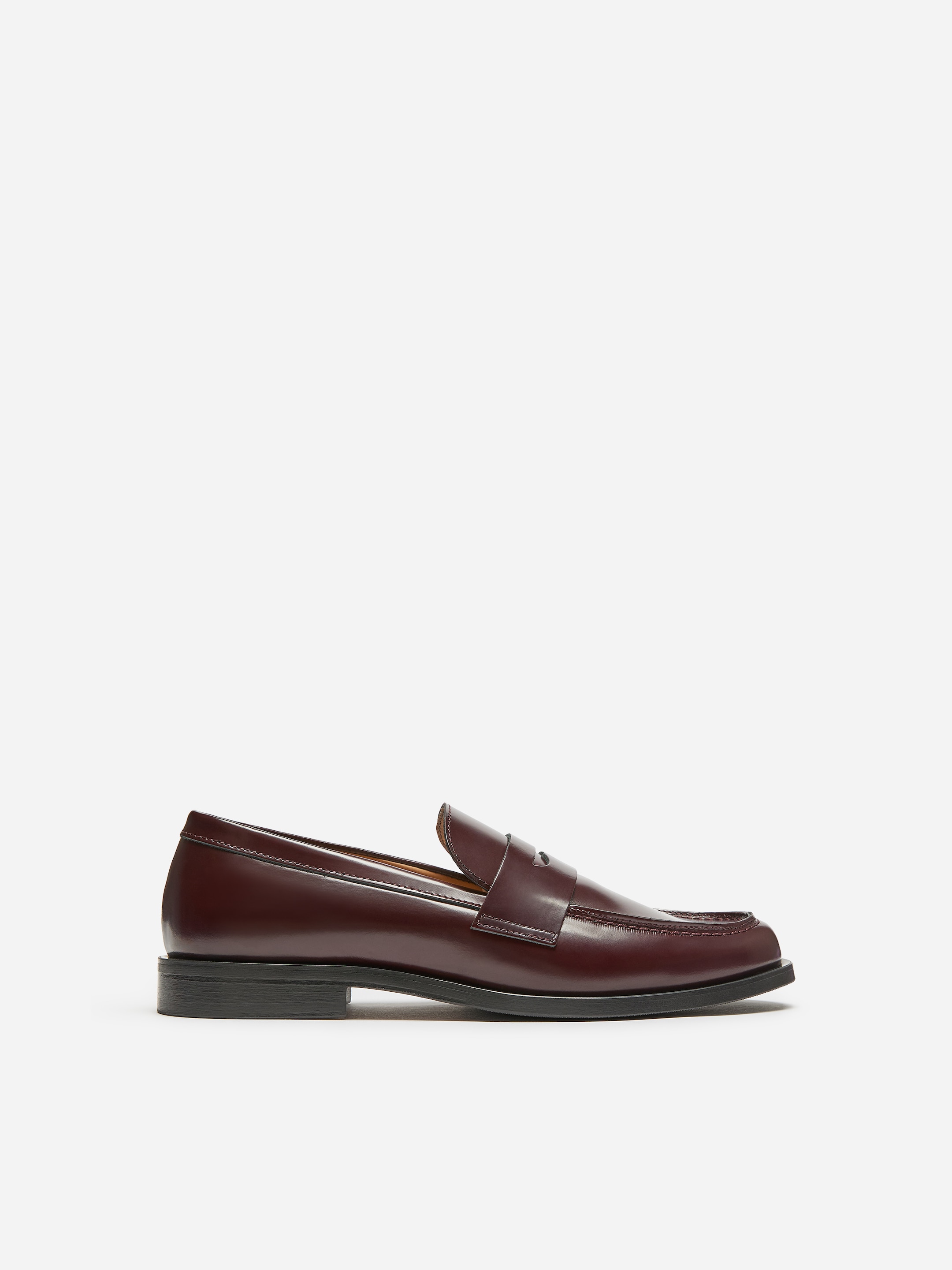 A classic burgundy leather loafer with a low heel, penny strap, and sleek design, viewed from the side against a white background.