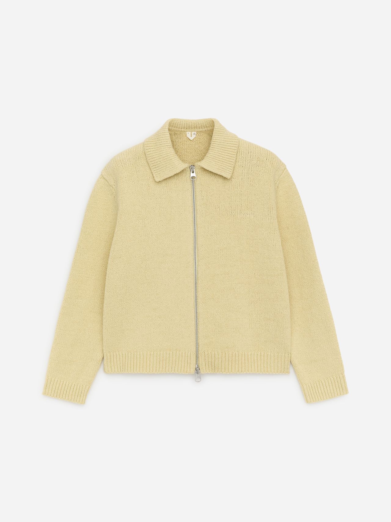 Cream-colored knitted cardigan with a front zipper and a pointed collar, laid flat on a plain white background.