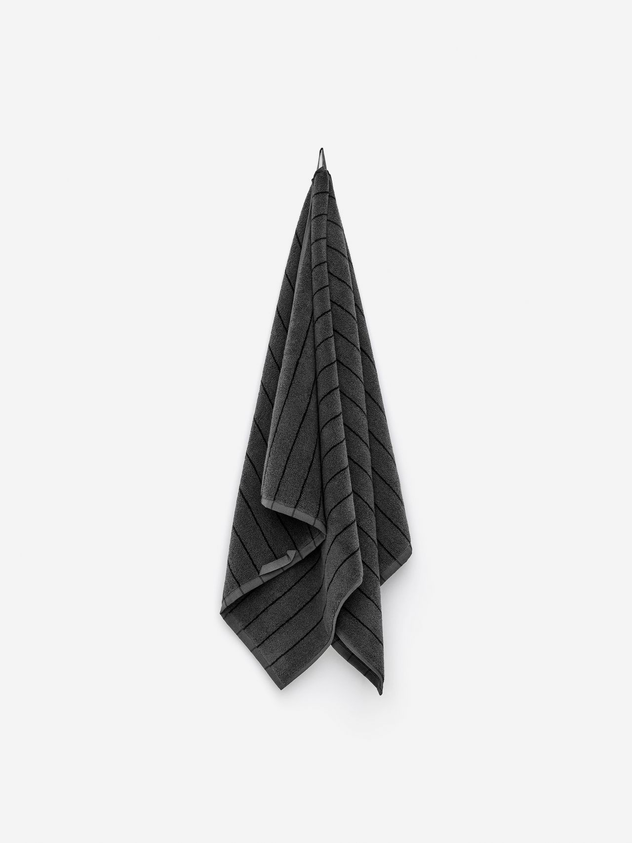A dark gray towel with diagonal stripes hangs on a hook against a white background.