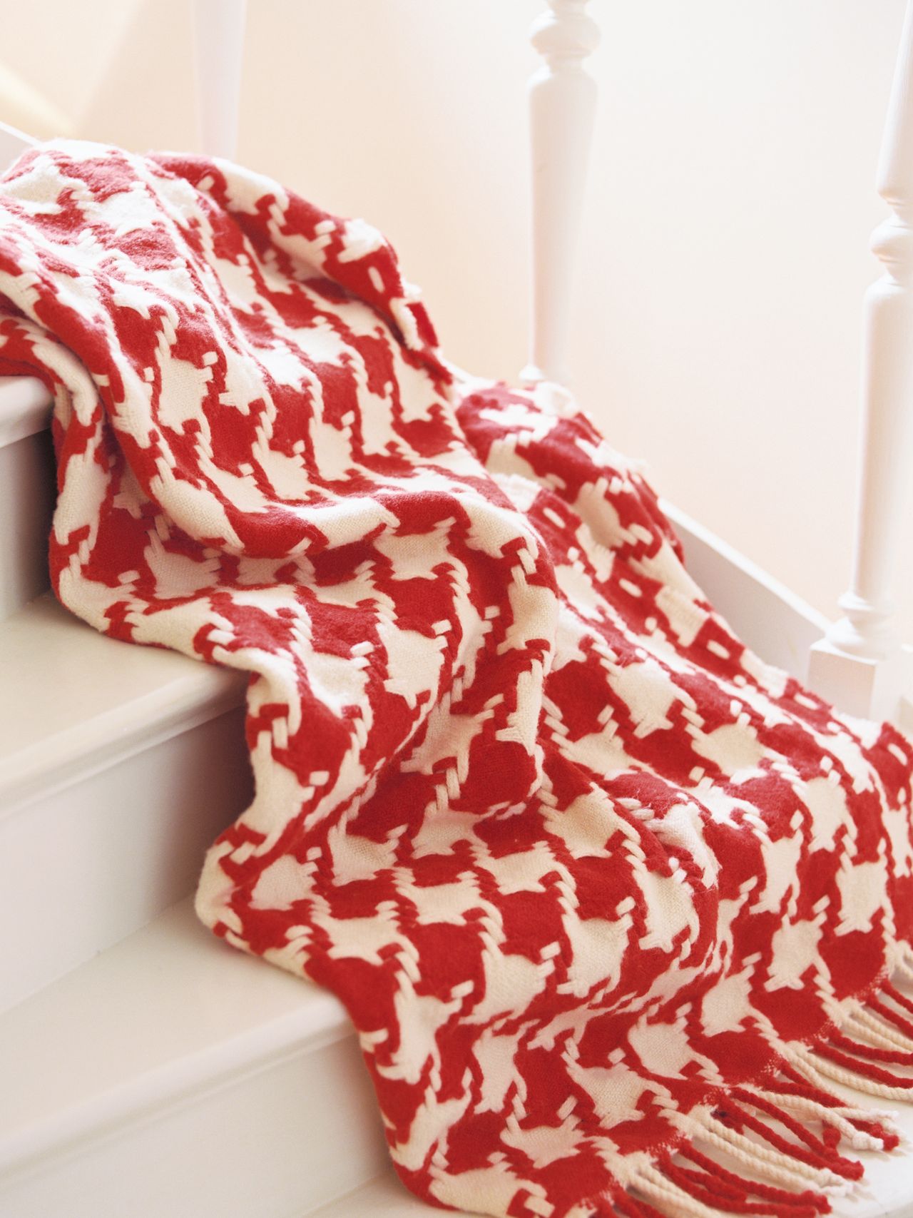 A red and white houndstooth-patterned blanket draped over white stairs, with soft lighting creating a cozy atmosphere.