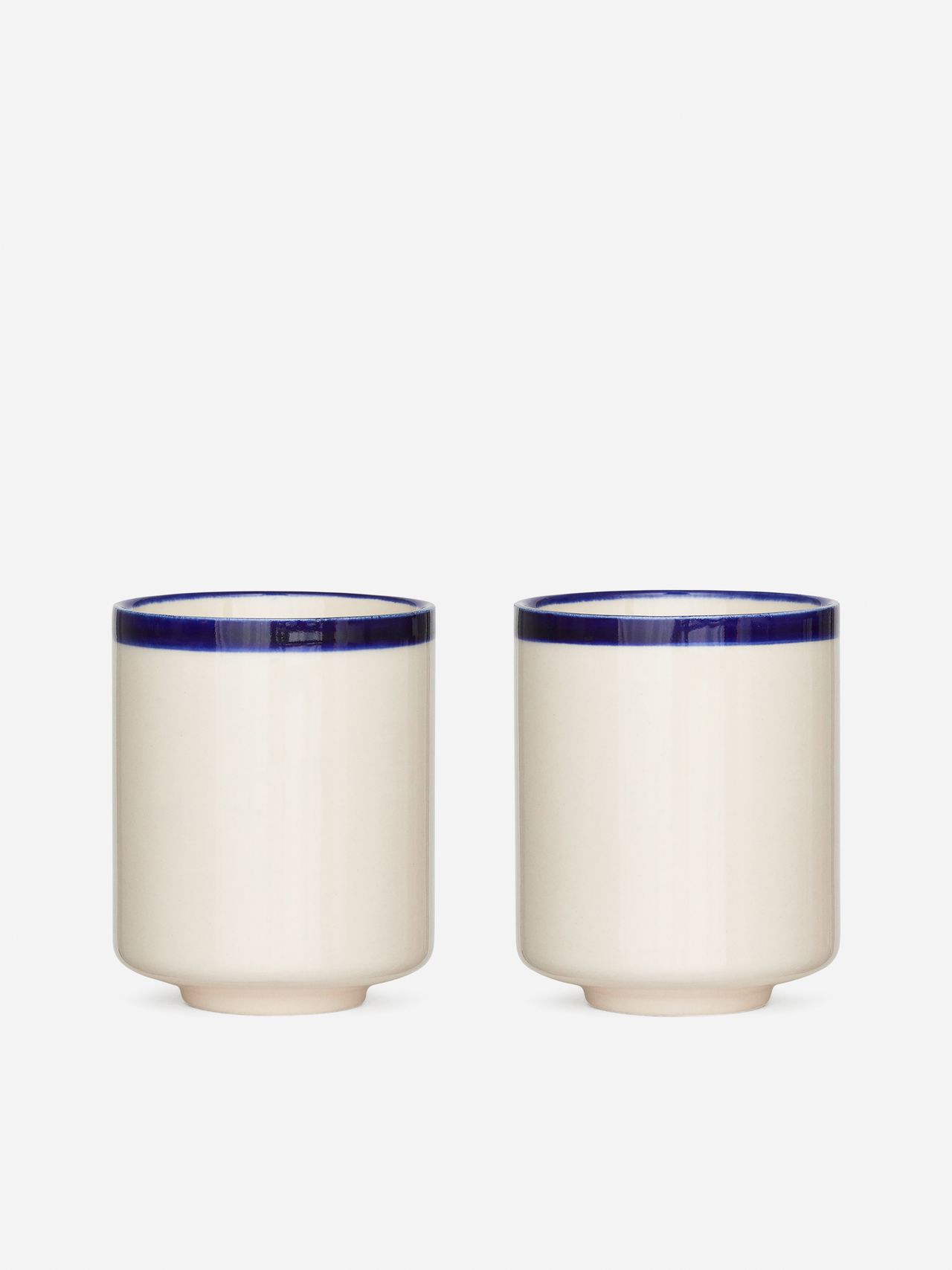 Two white ceramic cups with blue rims, placed side by side on a plain white background.