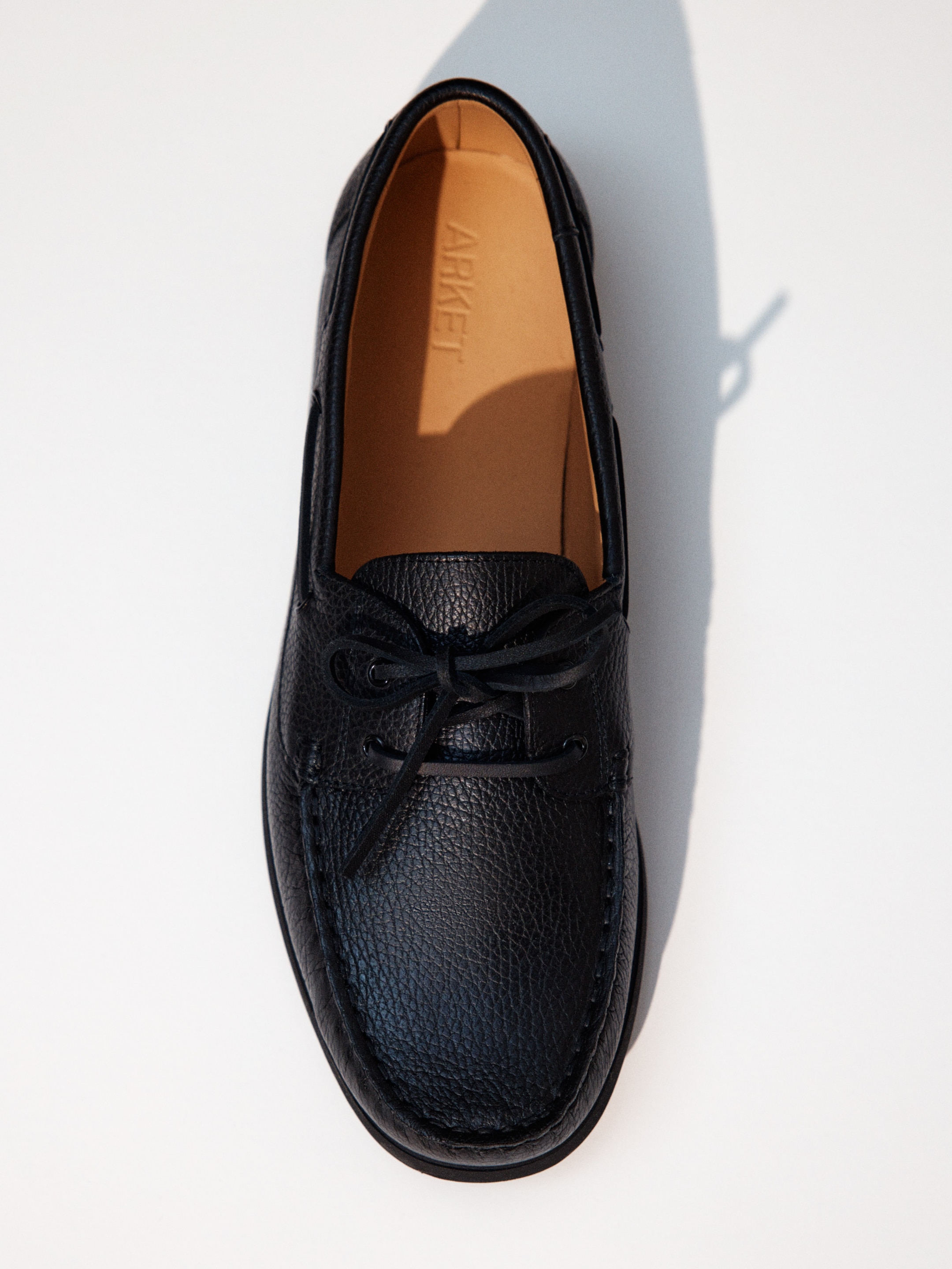 Black leather loafer with textured finish, viewed from above on a light background.