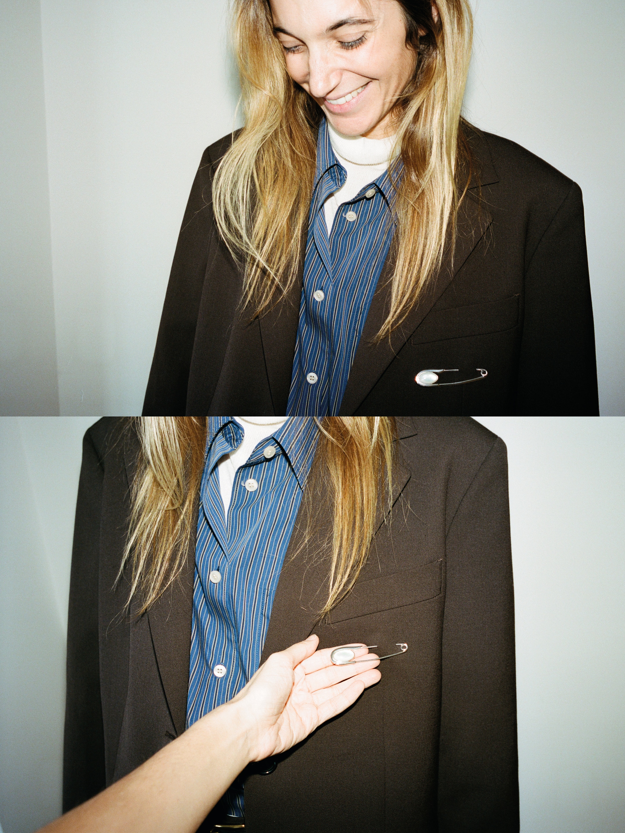 A person smiling, wearing a striped shirt under a brown blazer. Another hand is seen pinning a brooch to the blazer's pocket.
