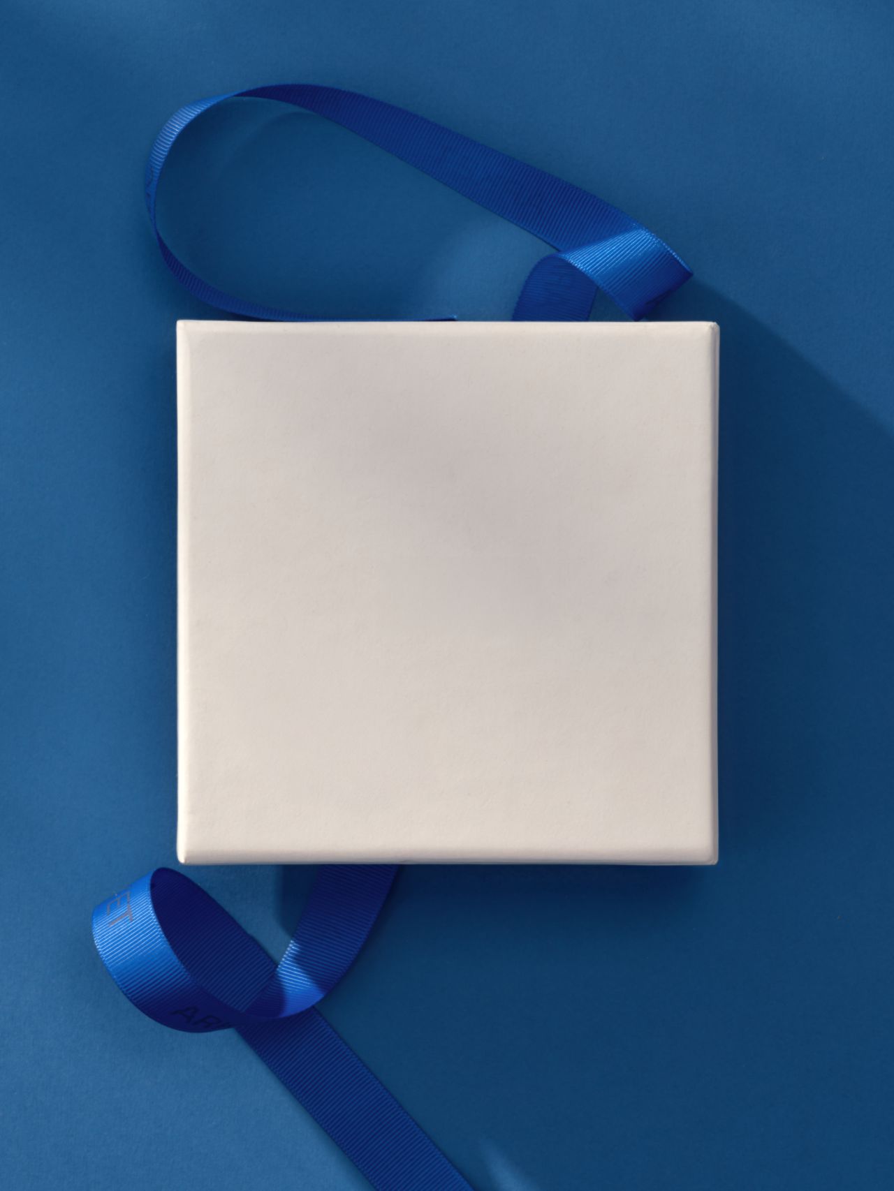 White square gift box with a blue ribbon on a blue background, casting a soft shadow.