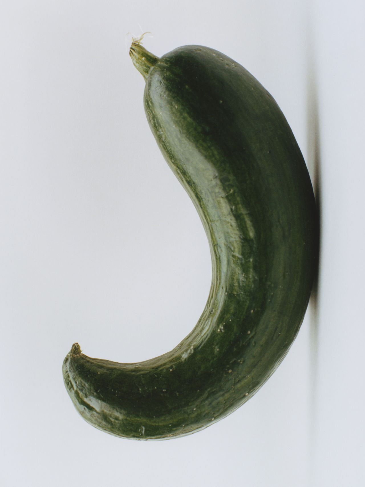 A curved, green cucumber against a plain white background.