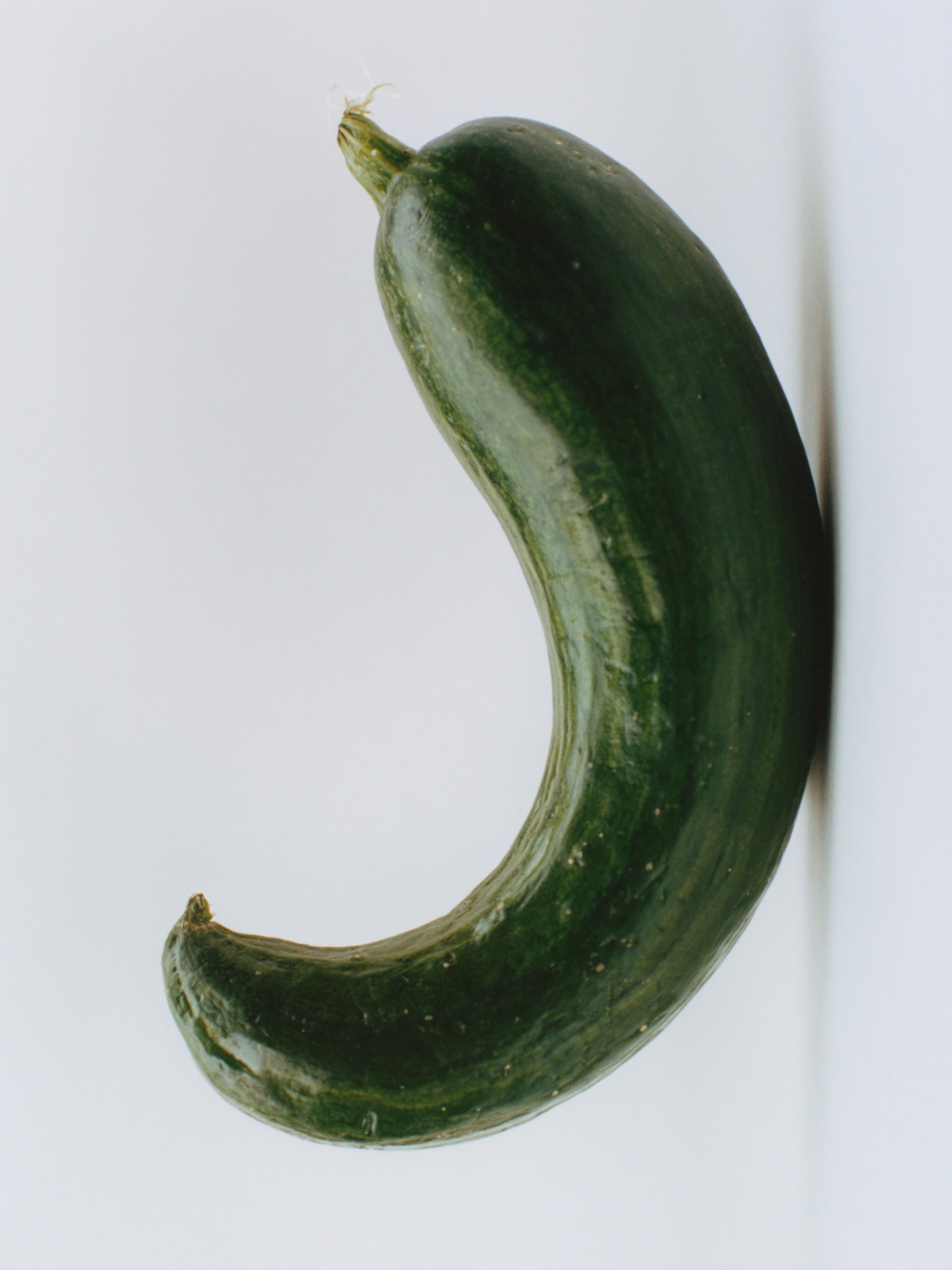A curved, green cucumber against a plain white background.