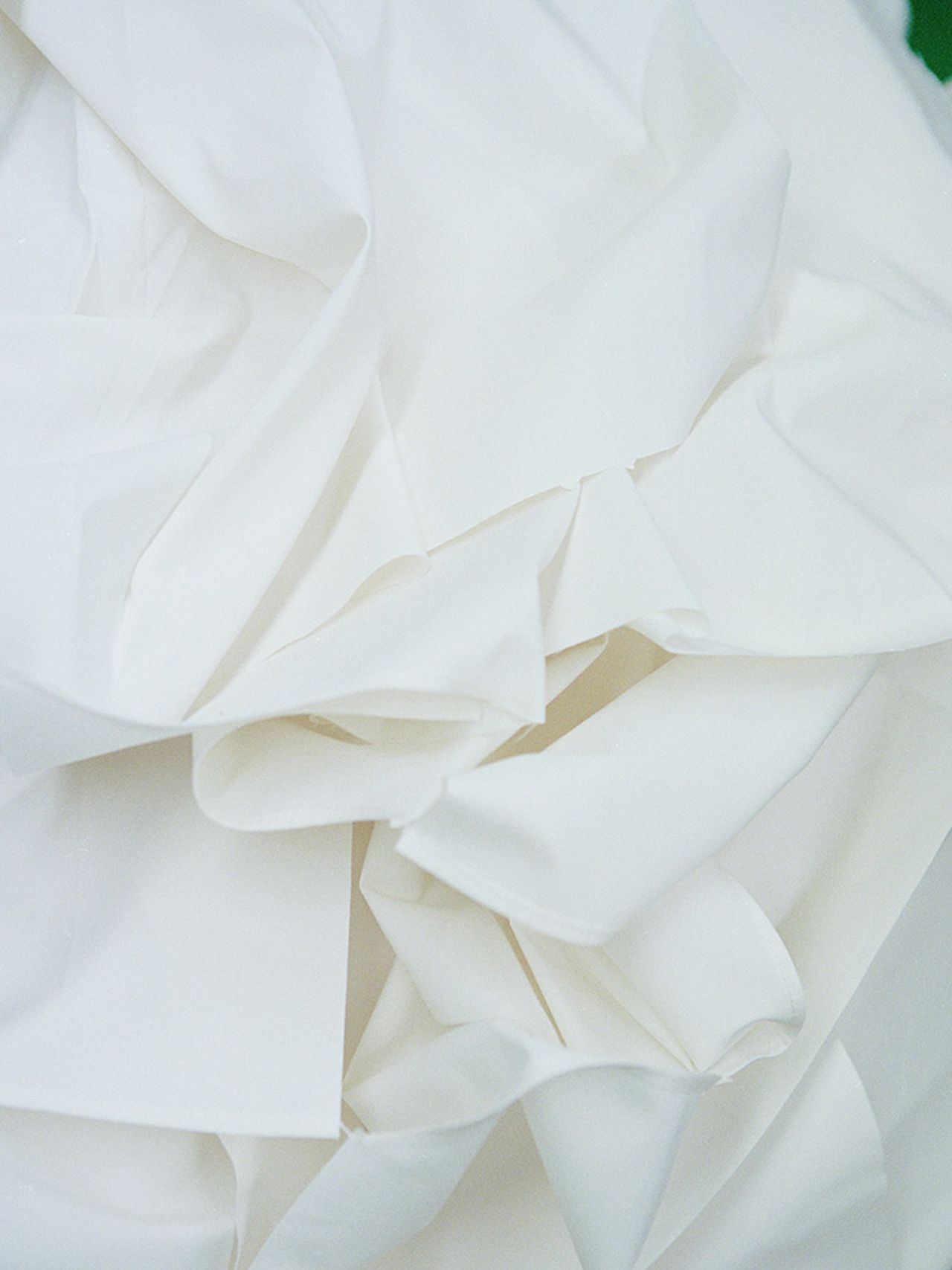 Crumpled white sheets of fabric soft folds and creases, creating a textured and abstract appearance.
