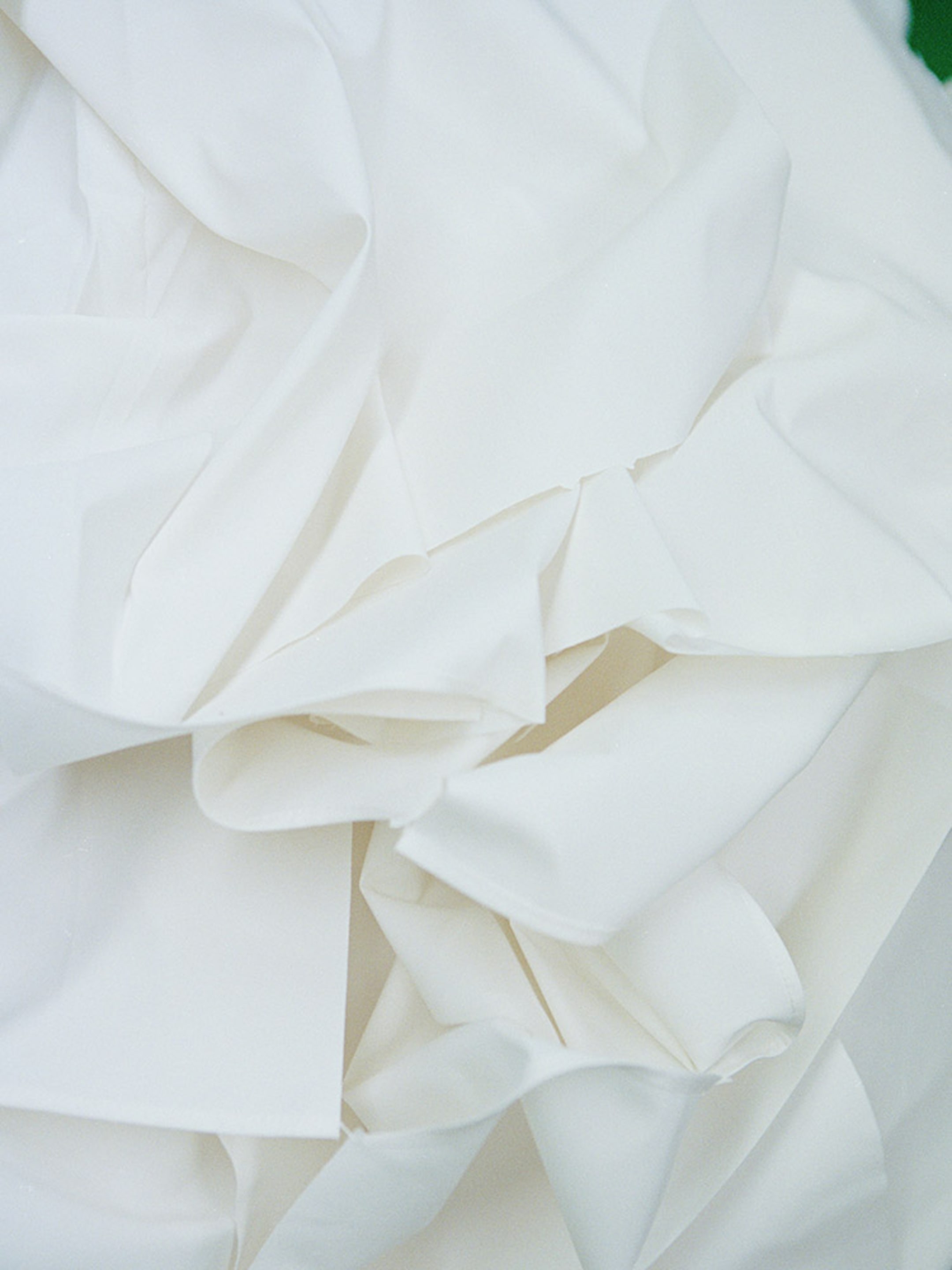 Crumpled white sheets of fabric soft folds and creases, creating a textured and abstract appearance.
