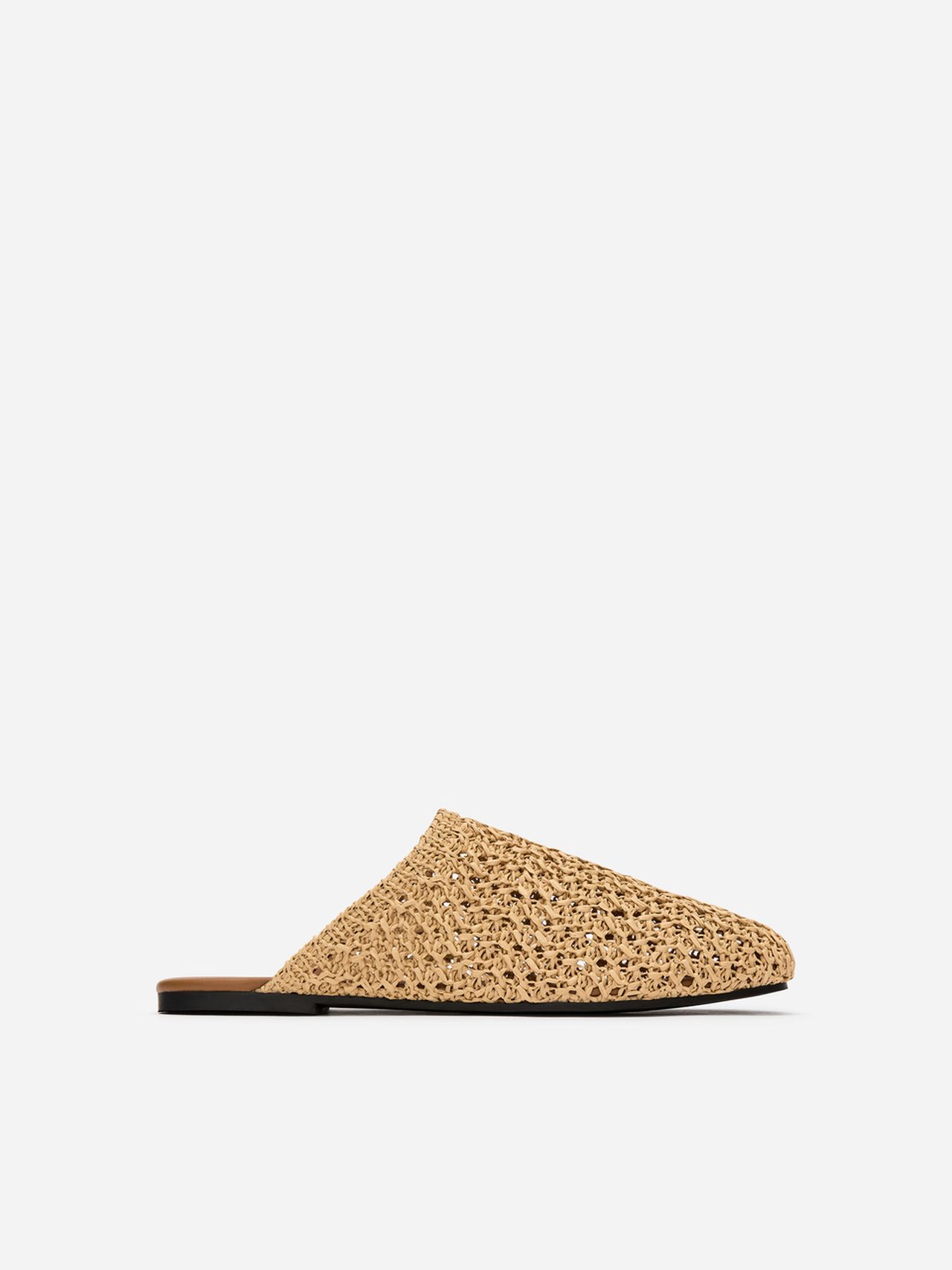 Woven straw sandal with a closed toe and open back, featuring a flat black sole, displayed on a plain white background.