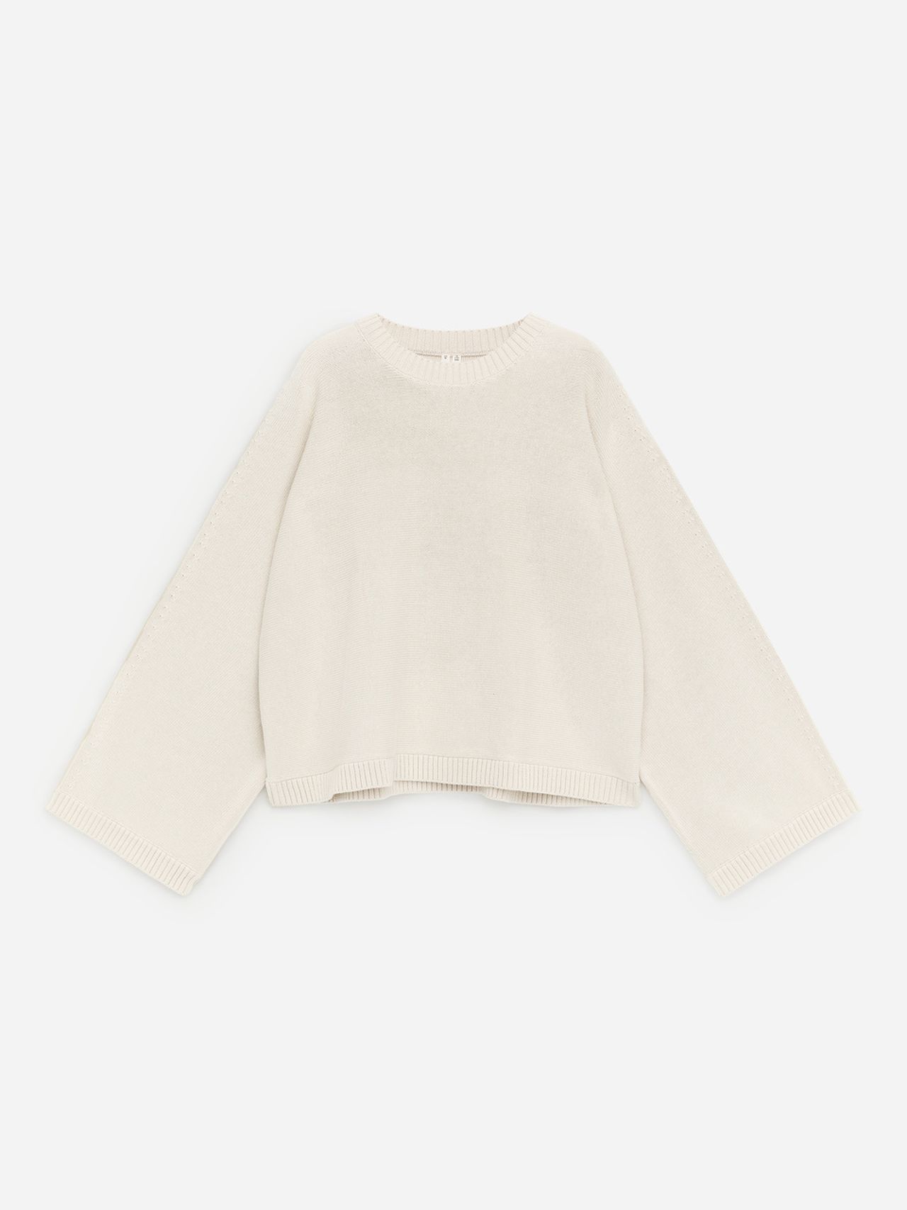Cream-colored, oversized knit sweater with long sleeves and a ribbed crew neckline, laid flat on a white background.