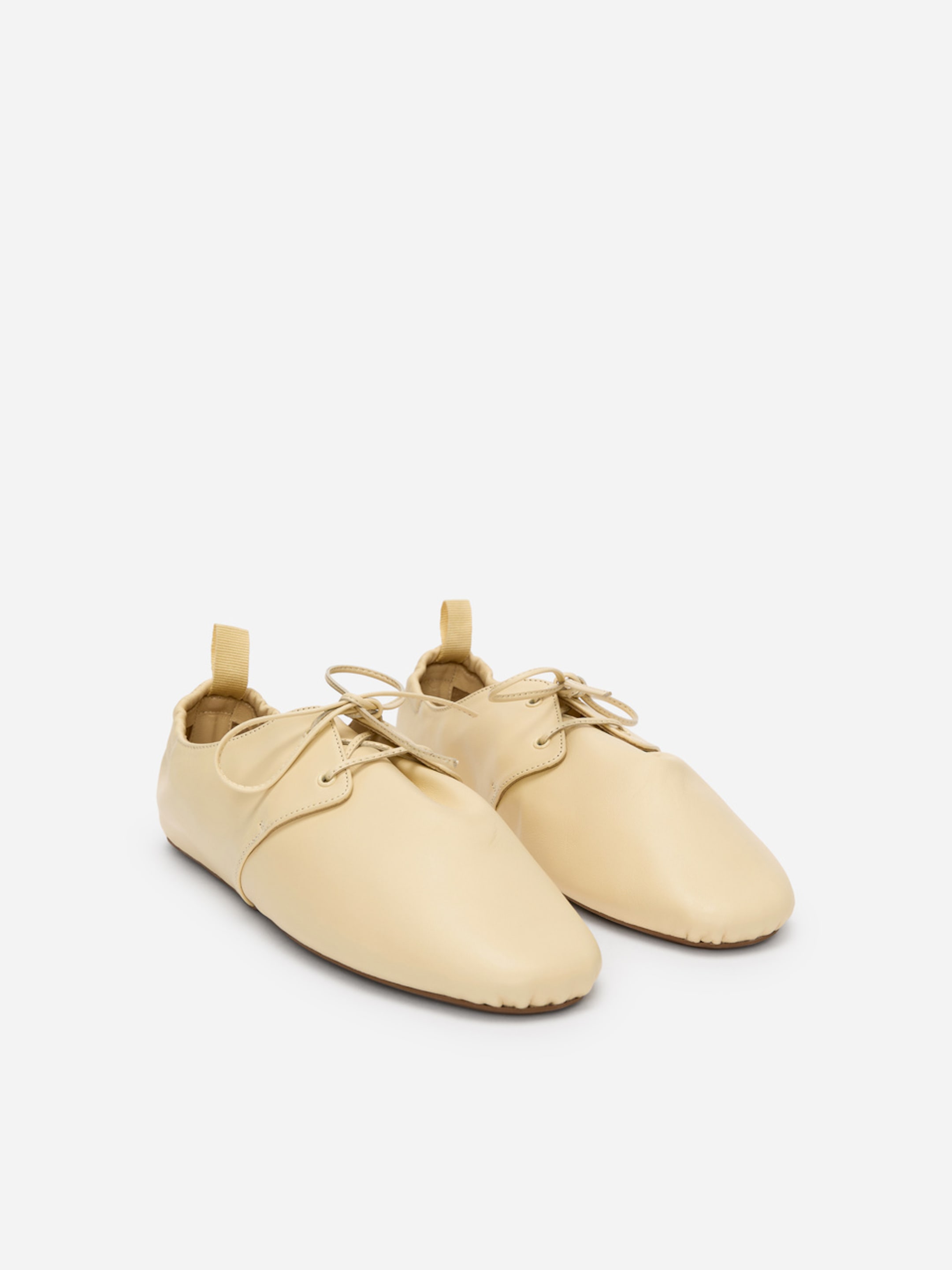 Beige leather flats with laces, featuring a minimalistic design and a soft finish.