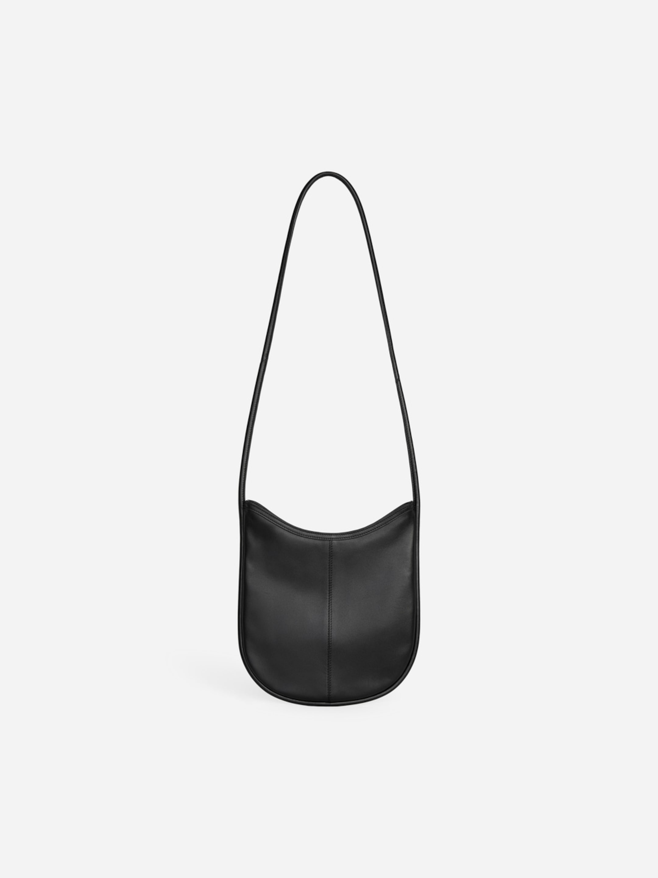 Black leather shoulder bag with a curved bottom and a long strap, set against a plain white background.